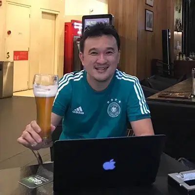 a man drinking a pint behind a laptop