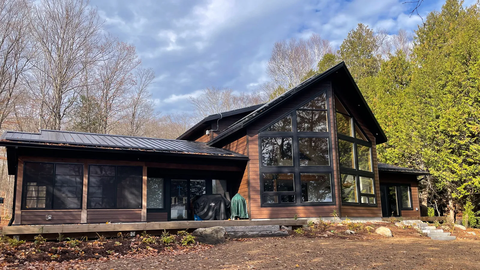 Peaked roof lake front summer home with large windows.