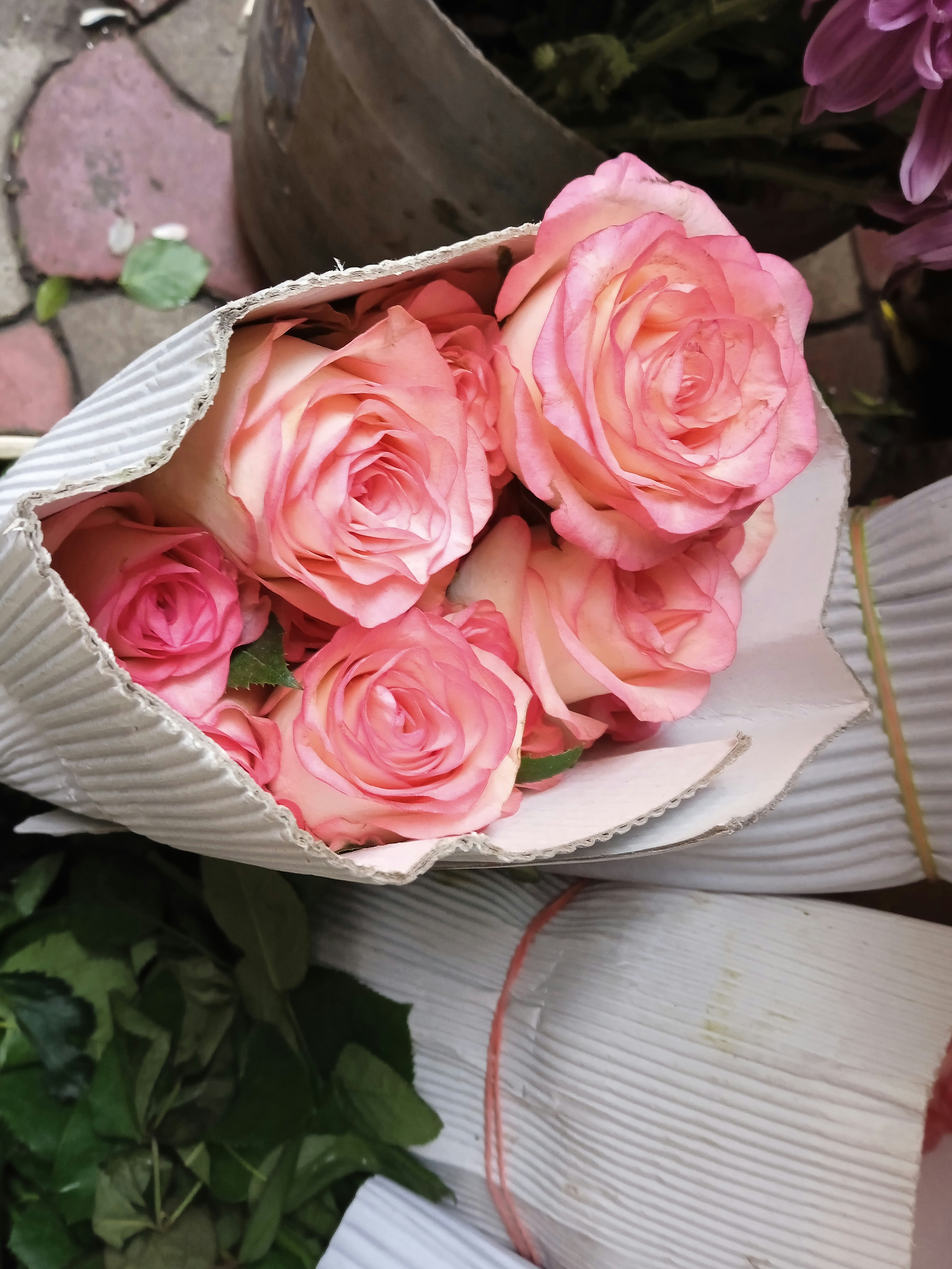 a bouquet of pink roses in a paper bag