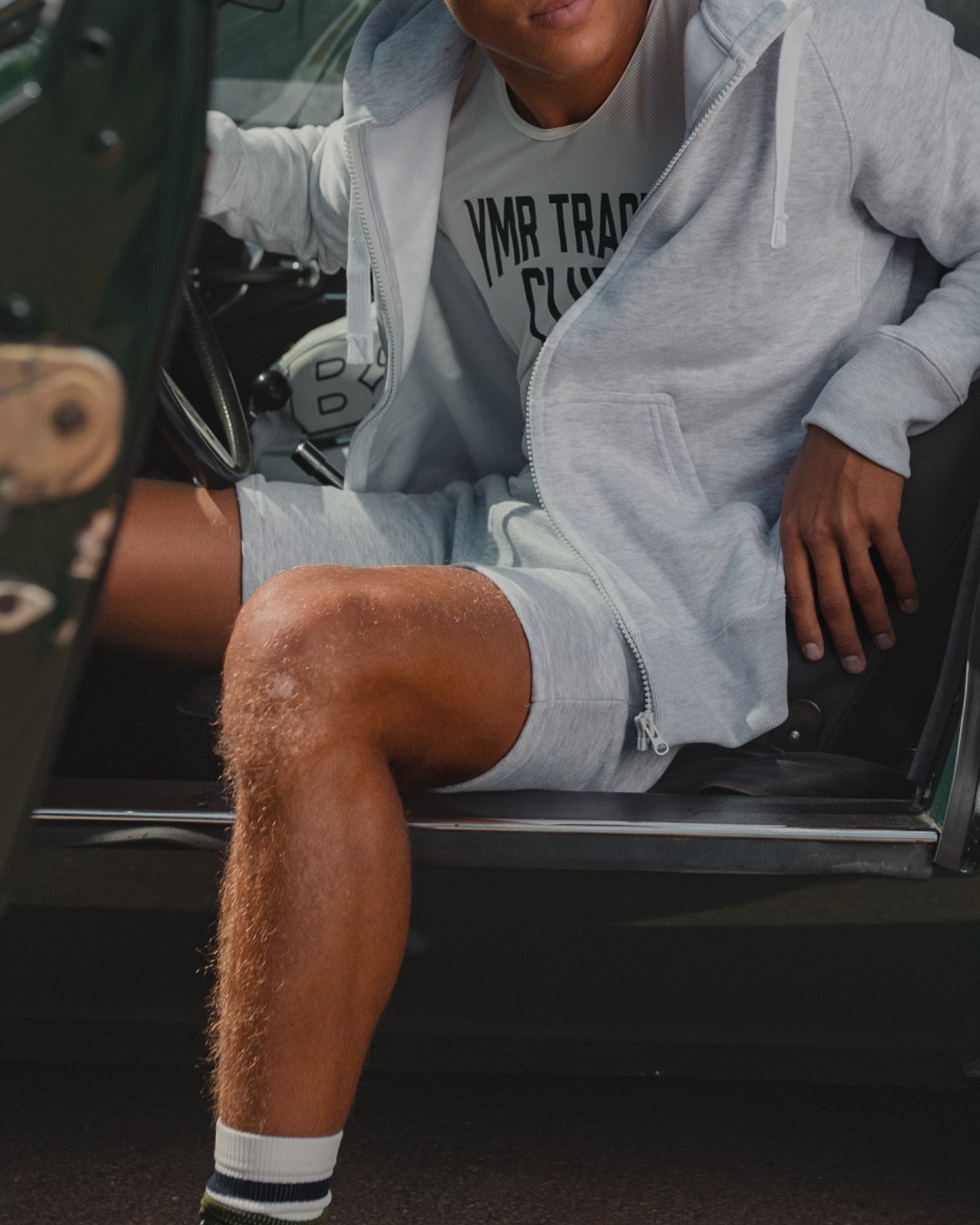 Person wearing a light grey shorts and ziphoodie while sitting in a car