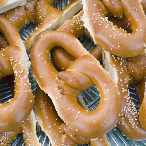 A stack of salted soft pretzels on a blue and white striped surface.