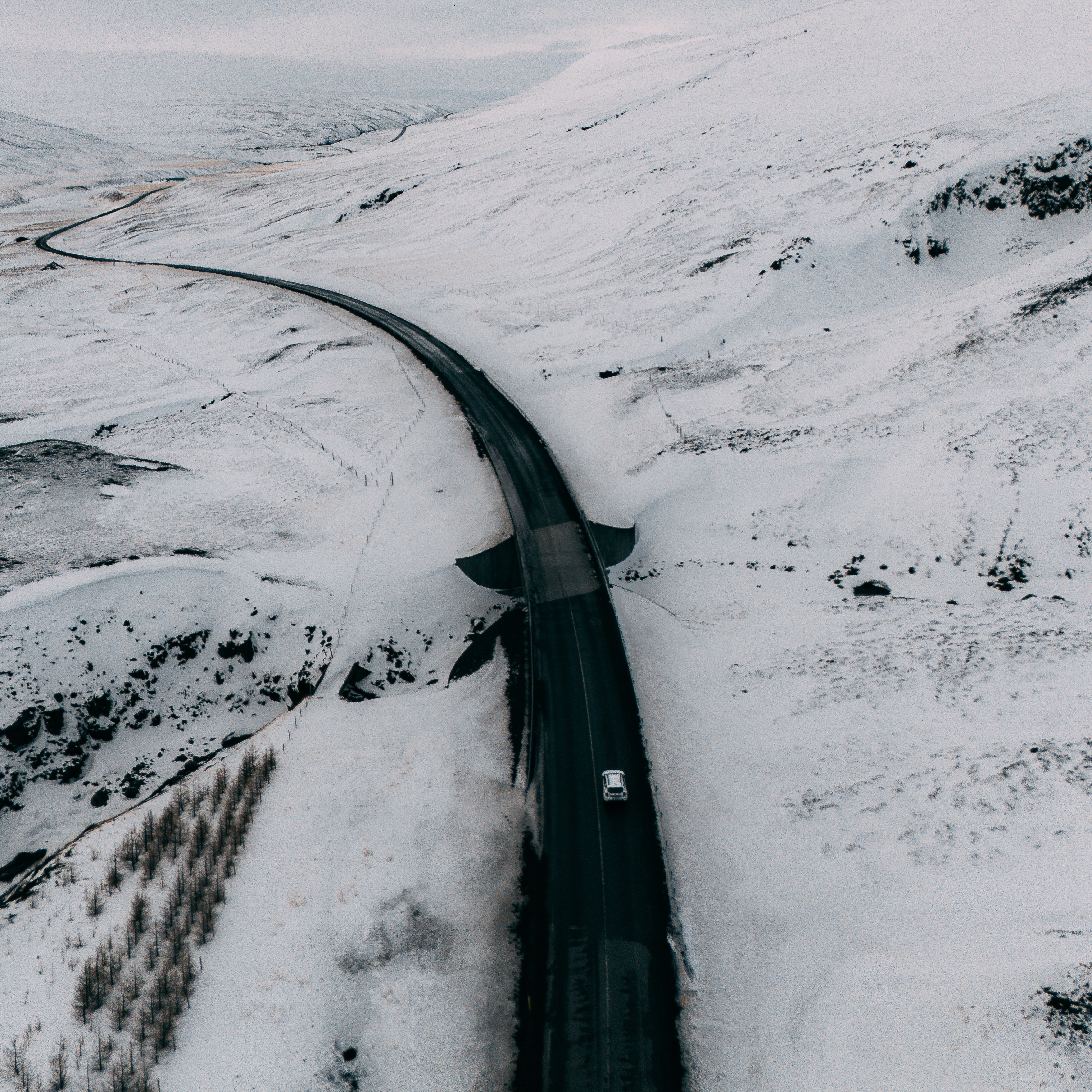 SUV driving on a snowy Icelandic road in winter weather conditions in Iceland