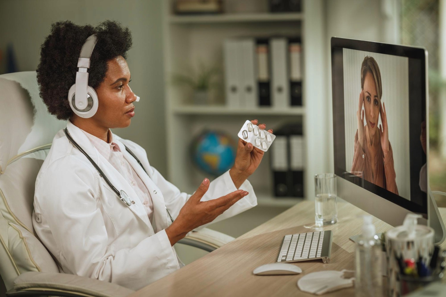 Shot of an african female doctor having video call with patient on computer in her office