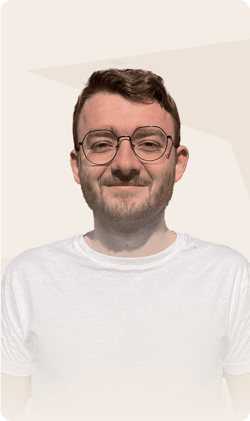 Portrait d'un homme portant des lunettes et un t-shirt blanc, souriant à la caméra.