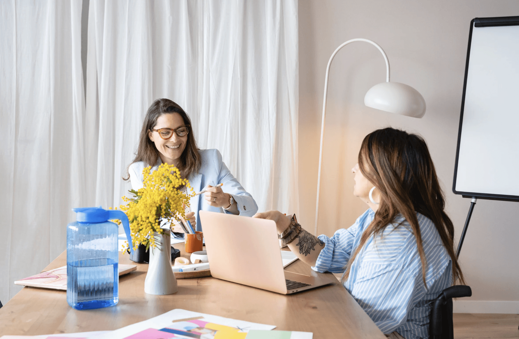 A serene and elegant spa space with wooden reclining chairs and white cushions. Golden sunlight filters through a cascading water feature, creating a peaceful atmosphere. Tropical plants and candles add to the relaxing ambiance.