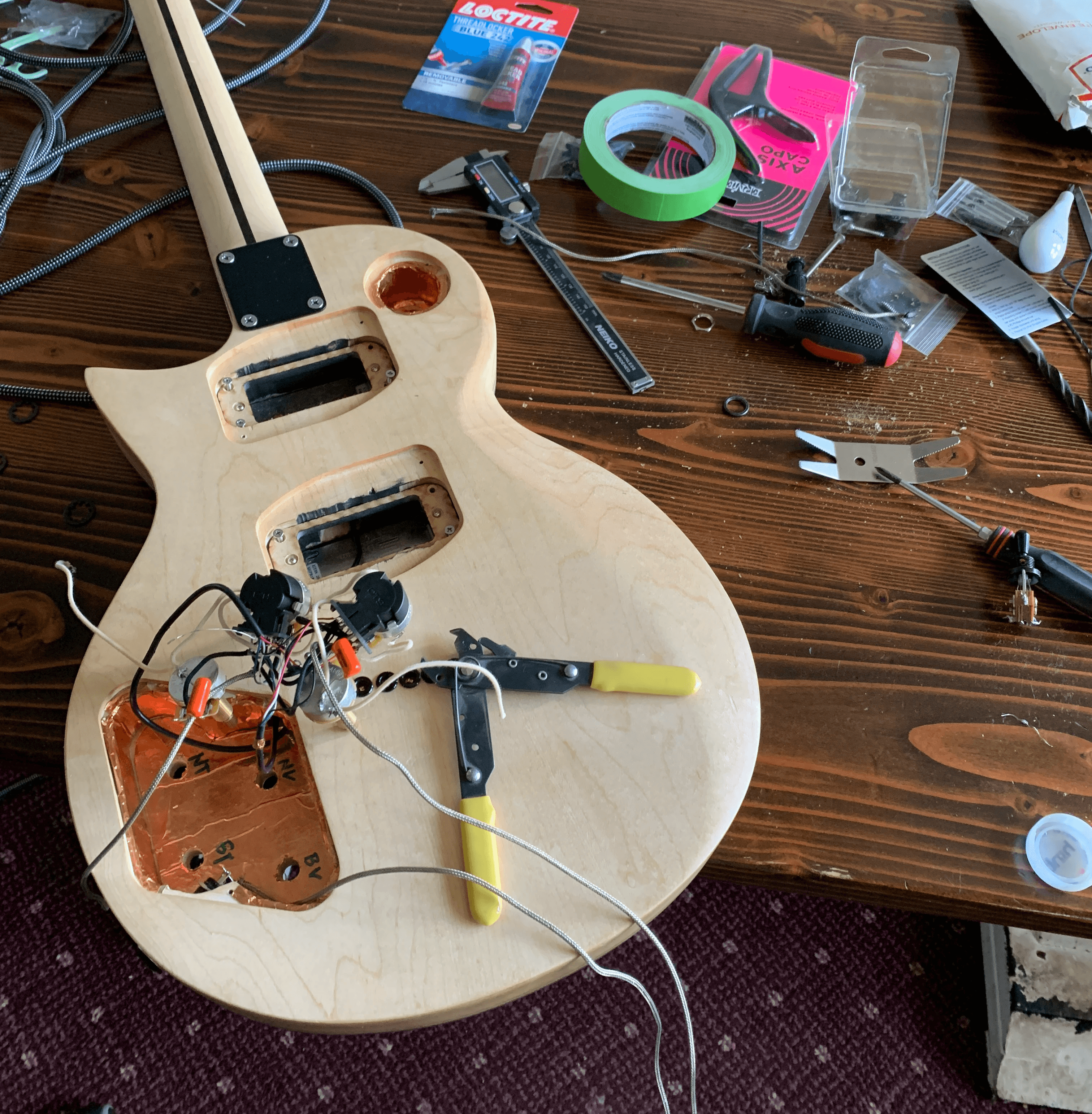 An electric guitar with the electronic components being assembled.