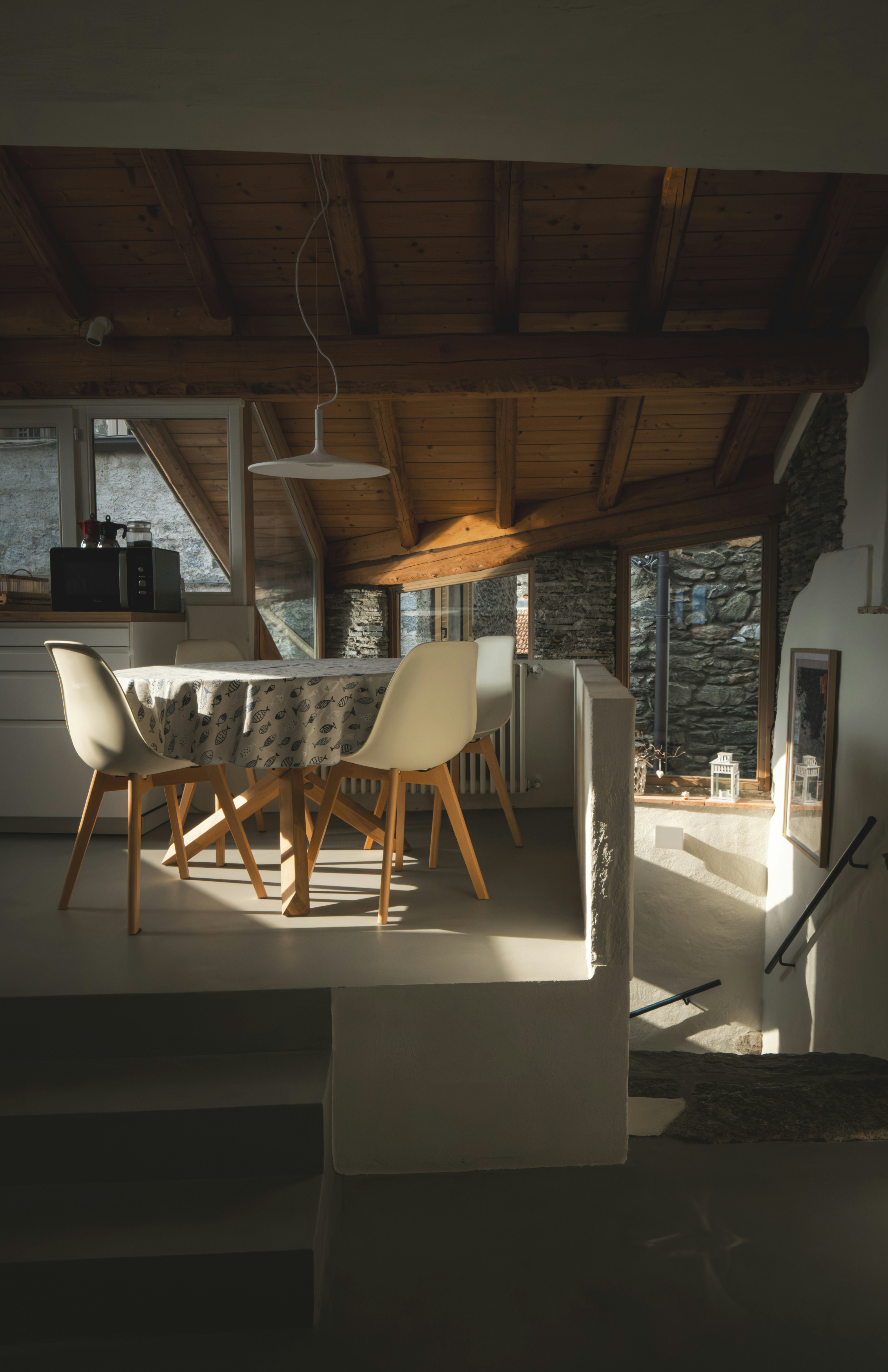 Dining area with chairs and table bathed in sunlight.