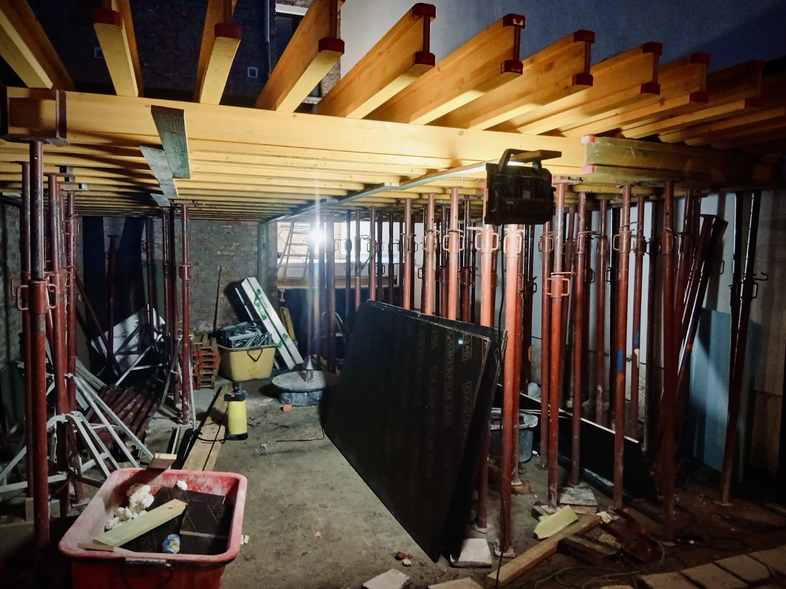 Building-site interior with red props and yellow beams.