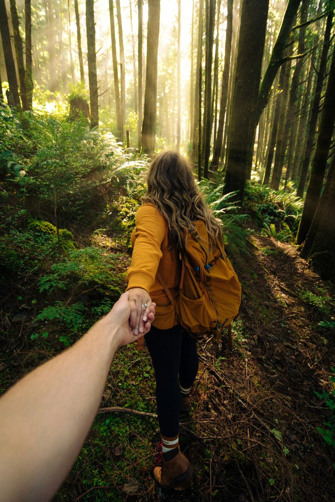 A woman guiding a friend along a scenic trail, symbolizing a commitment to embracing the outdoors with fluid connections between indoor workplaces and outdoor spaces.