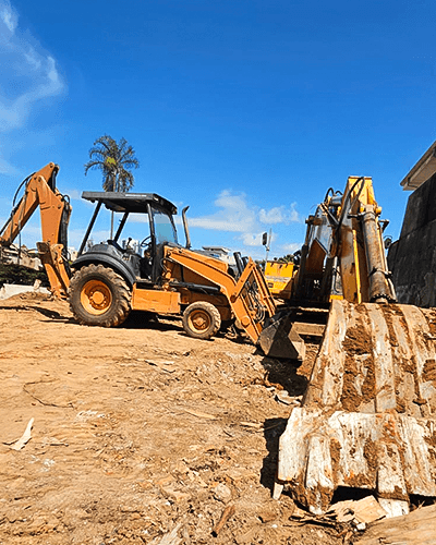 yellow excavator beside brown brick wall