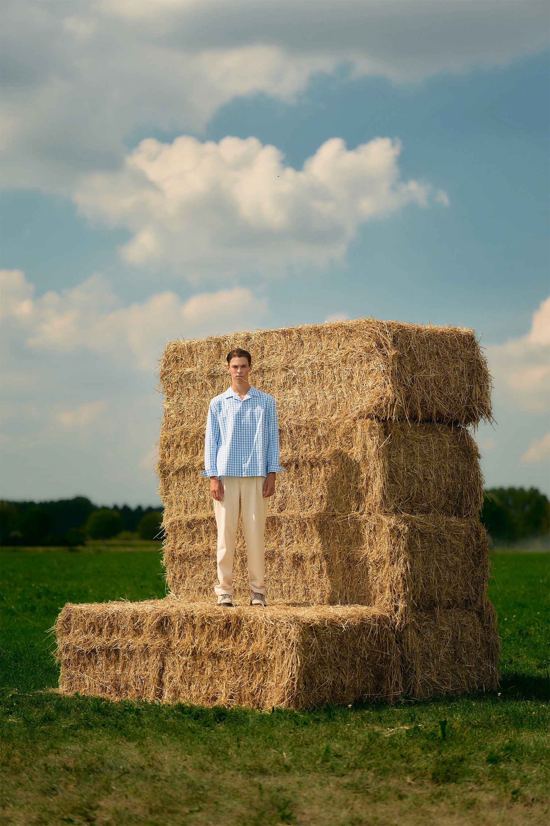 Sur des bottes de foin, le mannequin porte une chemise bleu à carreaux dans le lookbook Brams Fruit