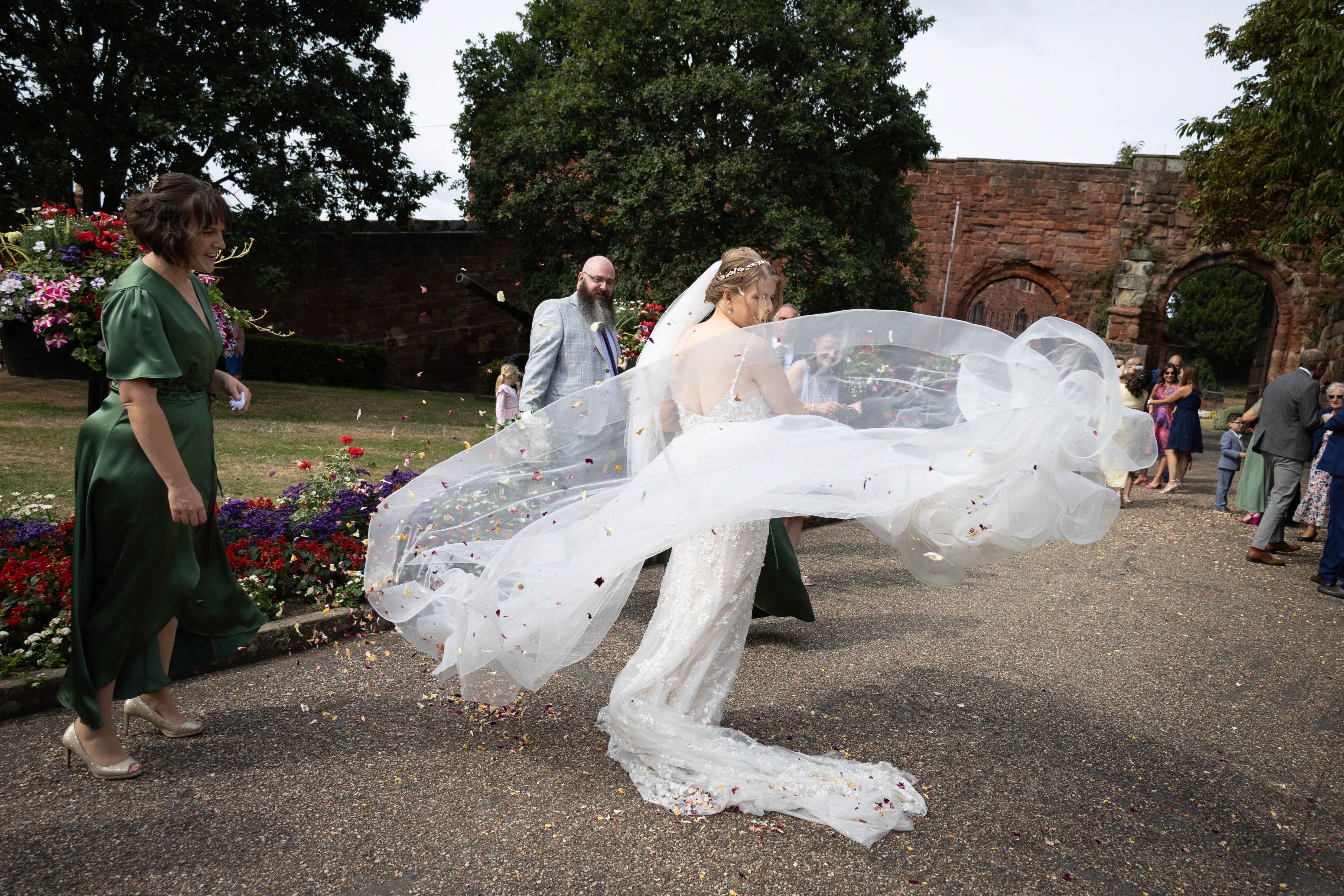 Becs twirling with her veil flowing through confetti outside Shrewsbury Castle after the ceremony