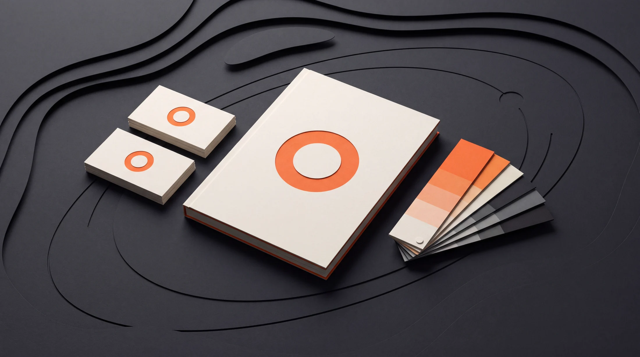 A cream brand booklet, matching business cards and orange, cream and charcoal swatches illustrate a consistent brand identity.