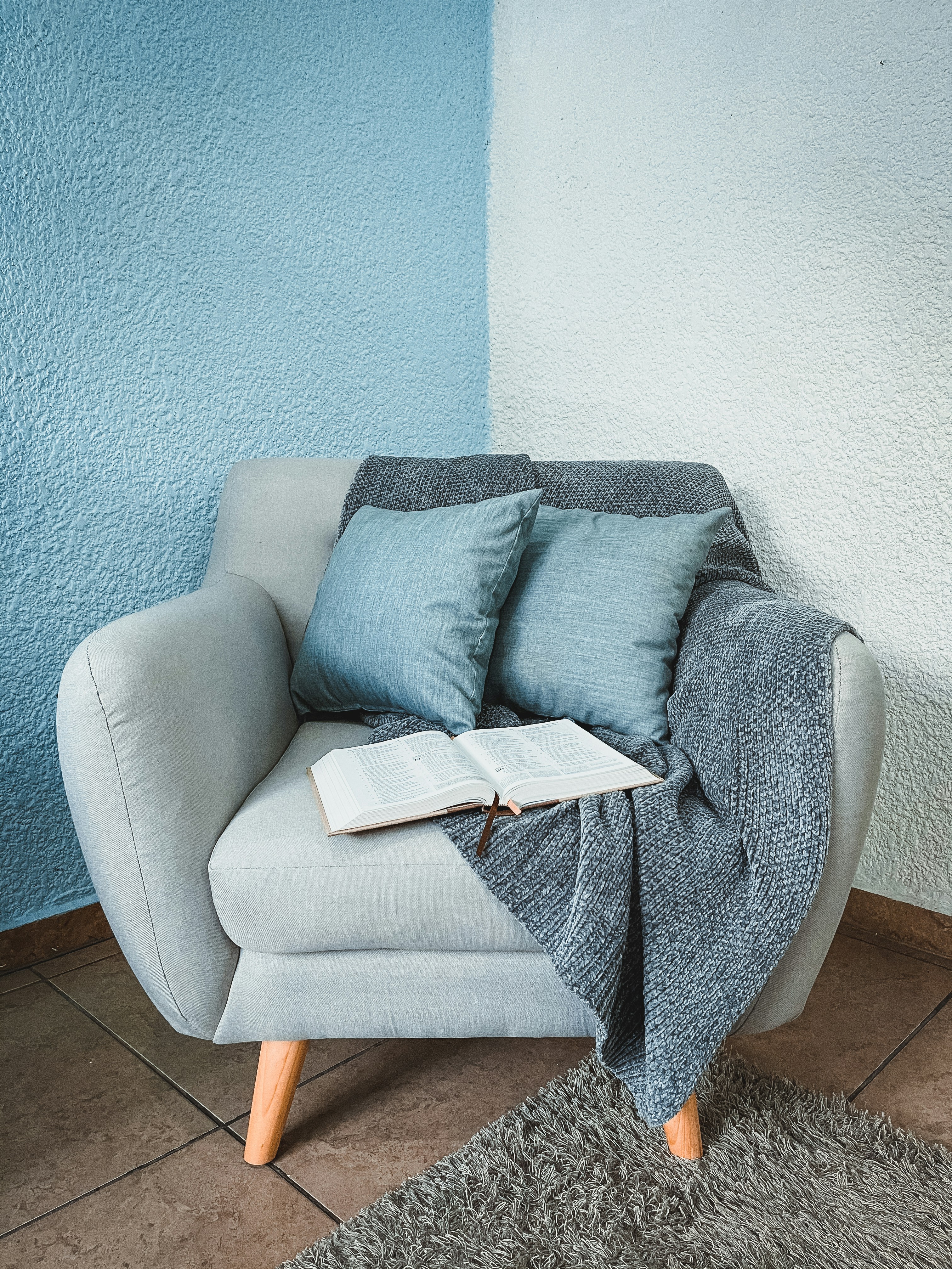 chair with blanket, pillows, and book