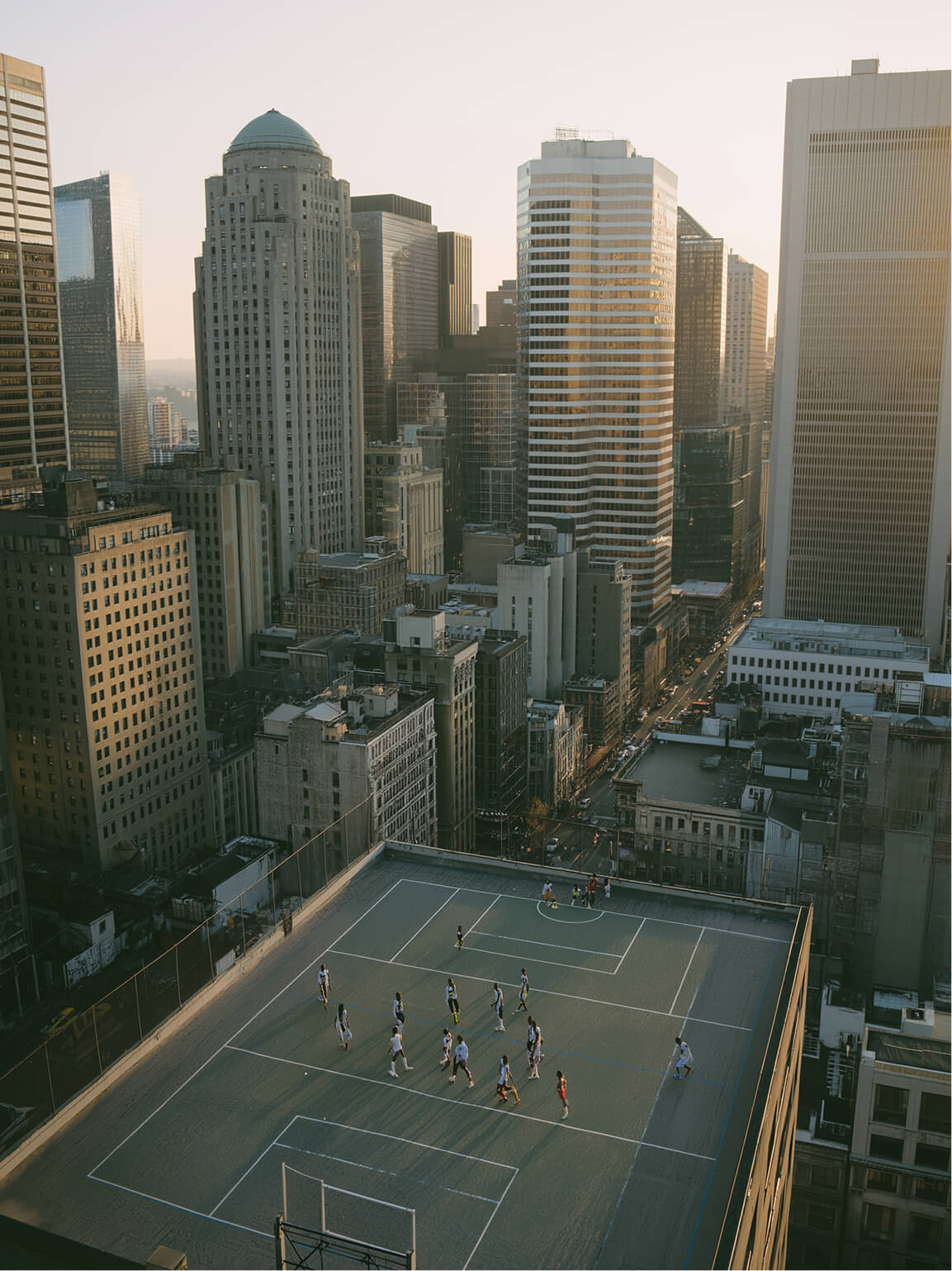 People playing soccer on a rooftop court surrounded by city buildings
