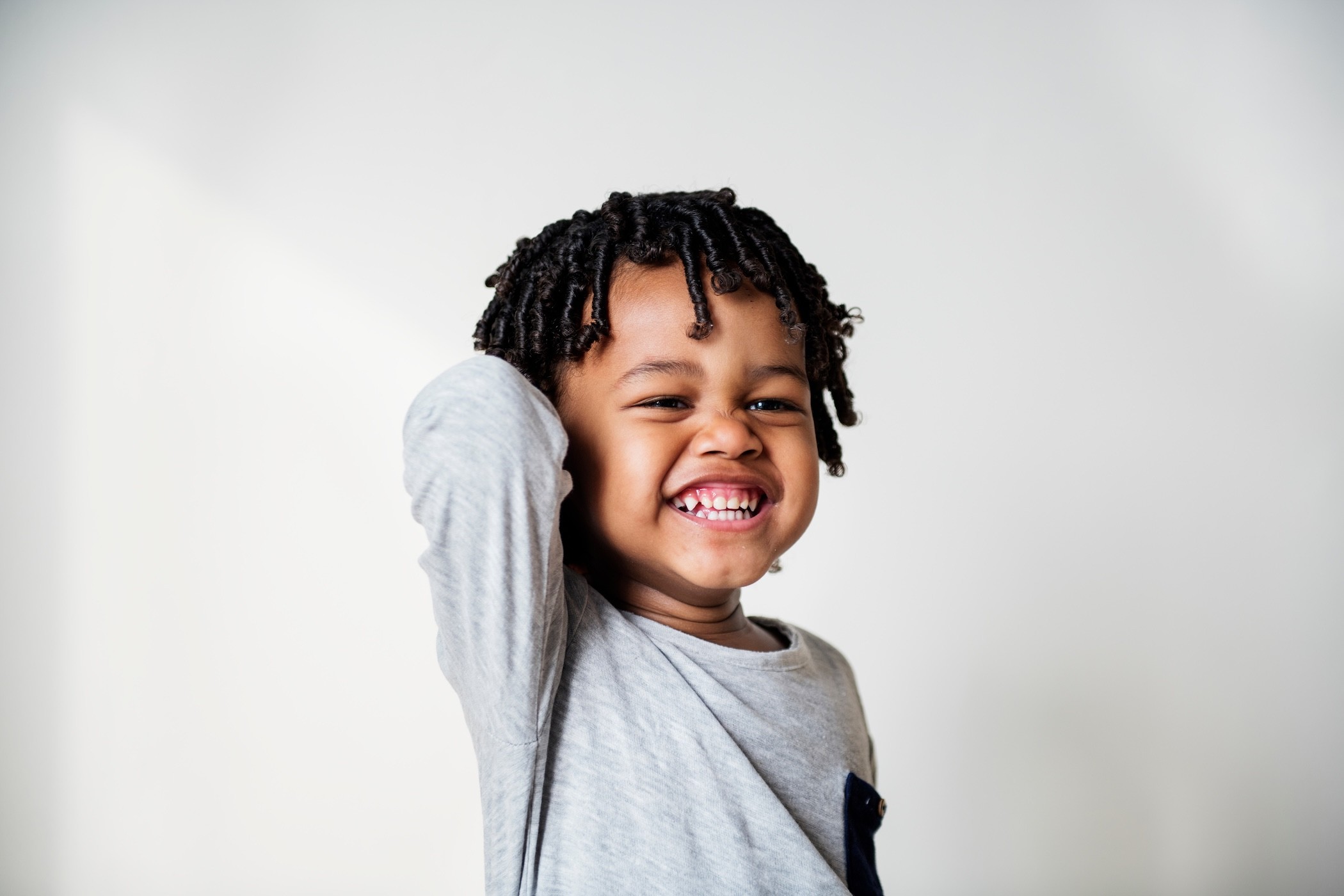 young kid smiling with teeth wide and scratching his head