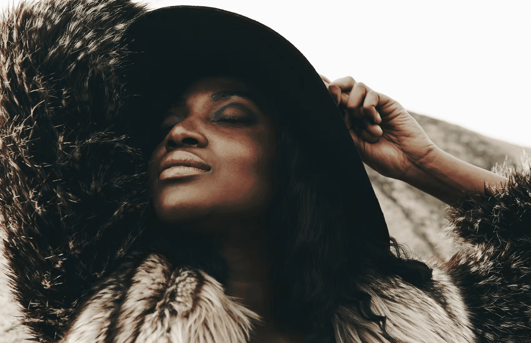 A winding road cuts through rocky terrain, surrounded by patches of green grass and illuminated by sunlight.