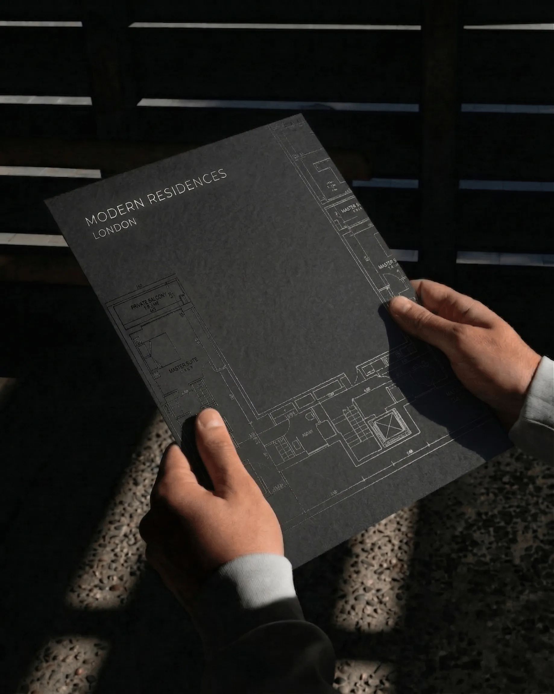 Hände halten hochwertigen schwarzen Grundrissplan eines Wohnprojekts — Projektidentität und Markenentwicklung für Immobilienentwickler und Projektentwicklung