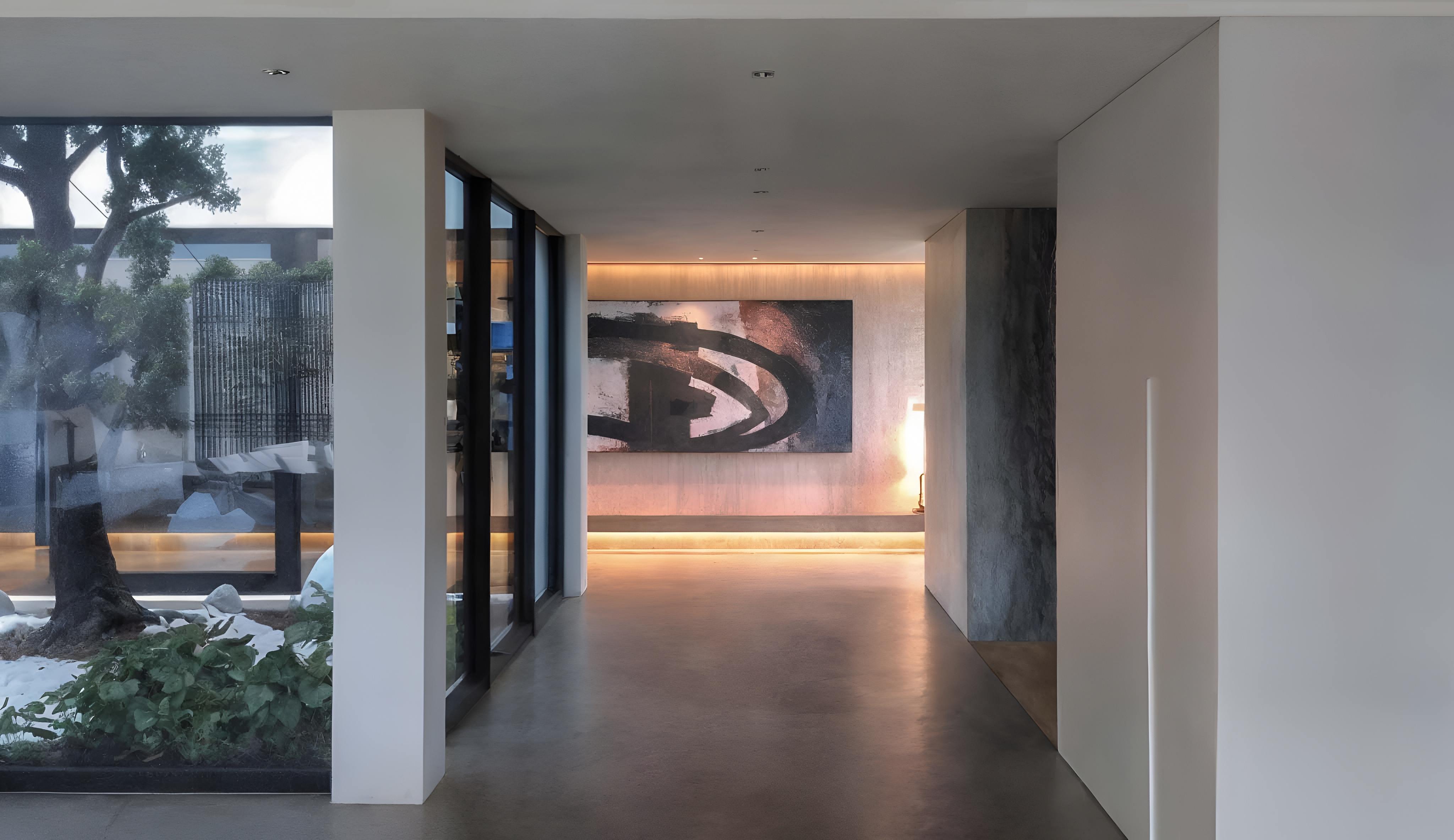 白色走廊一側為大型玻璃窗與日式造景，盡頭展示抽象畫作與間接照明，強化空間藝術氛圍