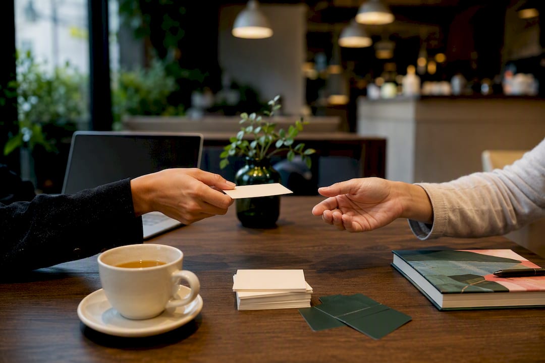 Hand passing business card on table