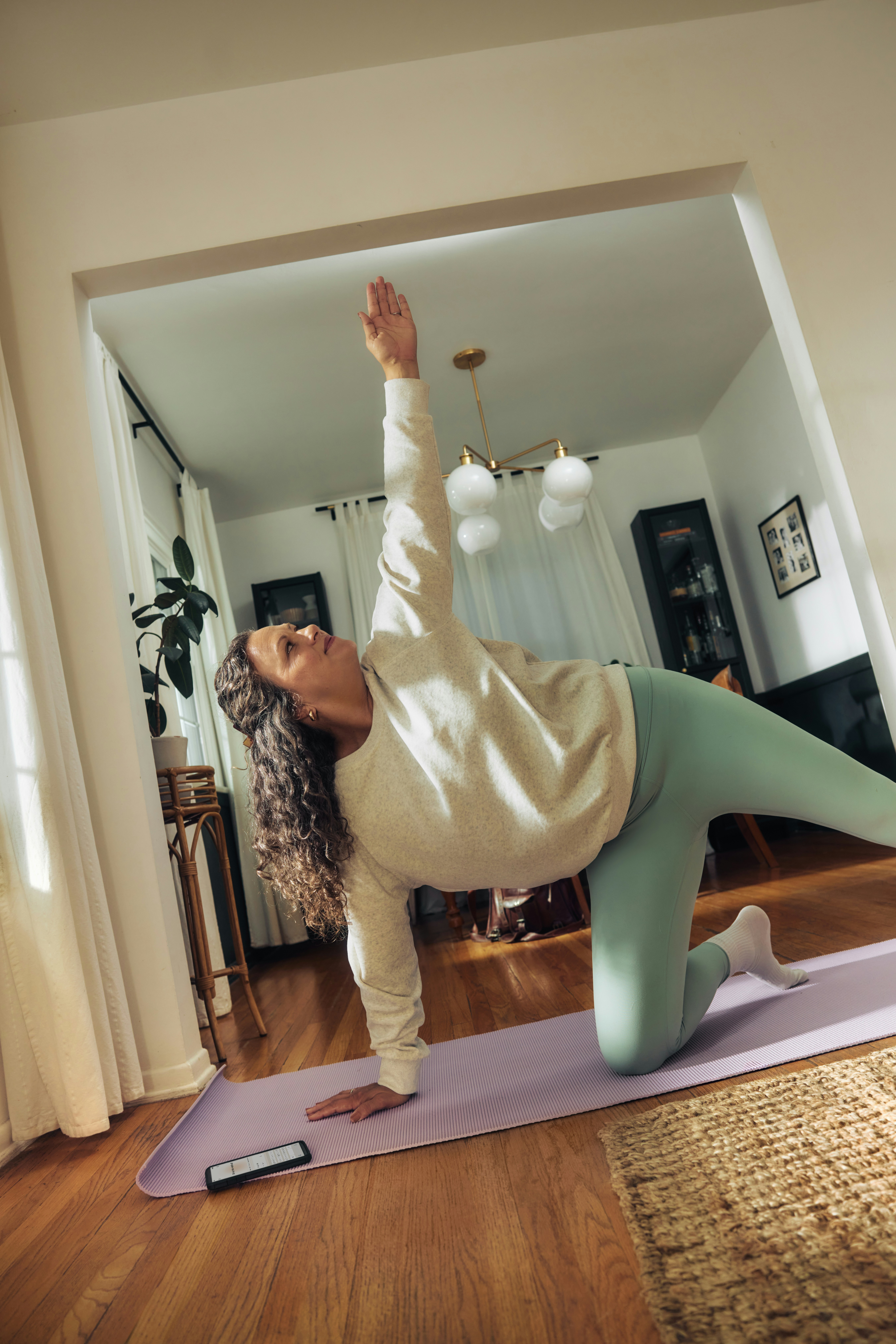 A woman does a yoga pose on a mat.