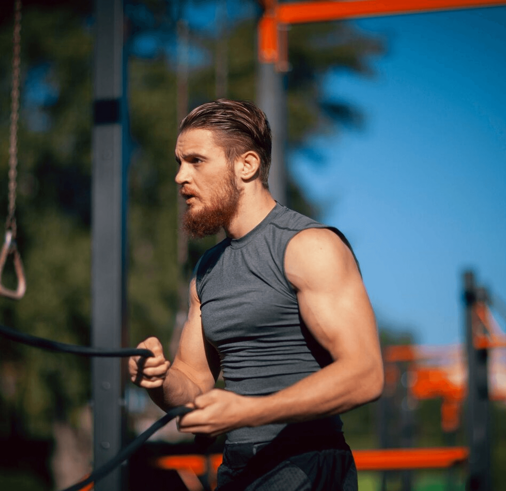 Man exercising with battle ropes at an outdoor gym.