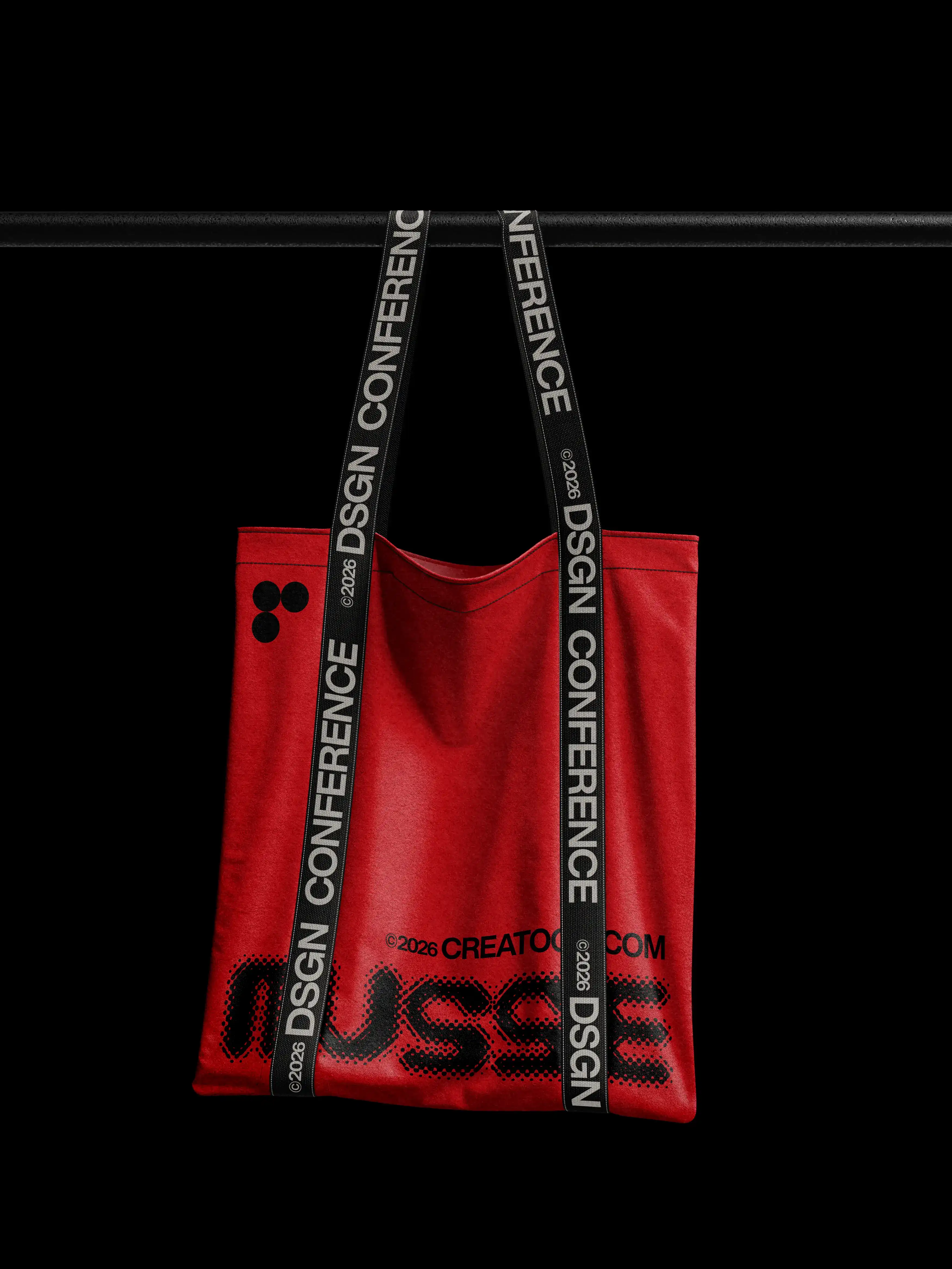 Red tote bag with black conference straps hanging from bar