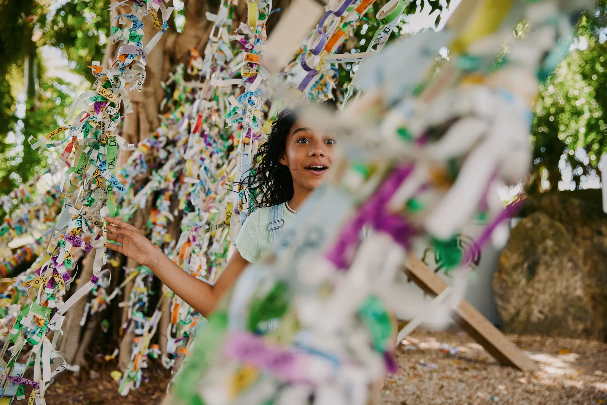 girl reaching toward ribbon covered tree — lifestyle photography by Tom Kubik