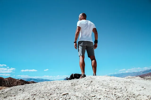 Man standing outdoors under a clear blue sky after physical effort in warm weather