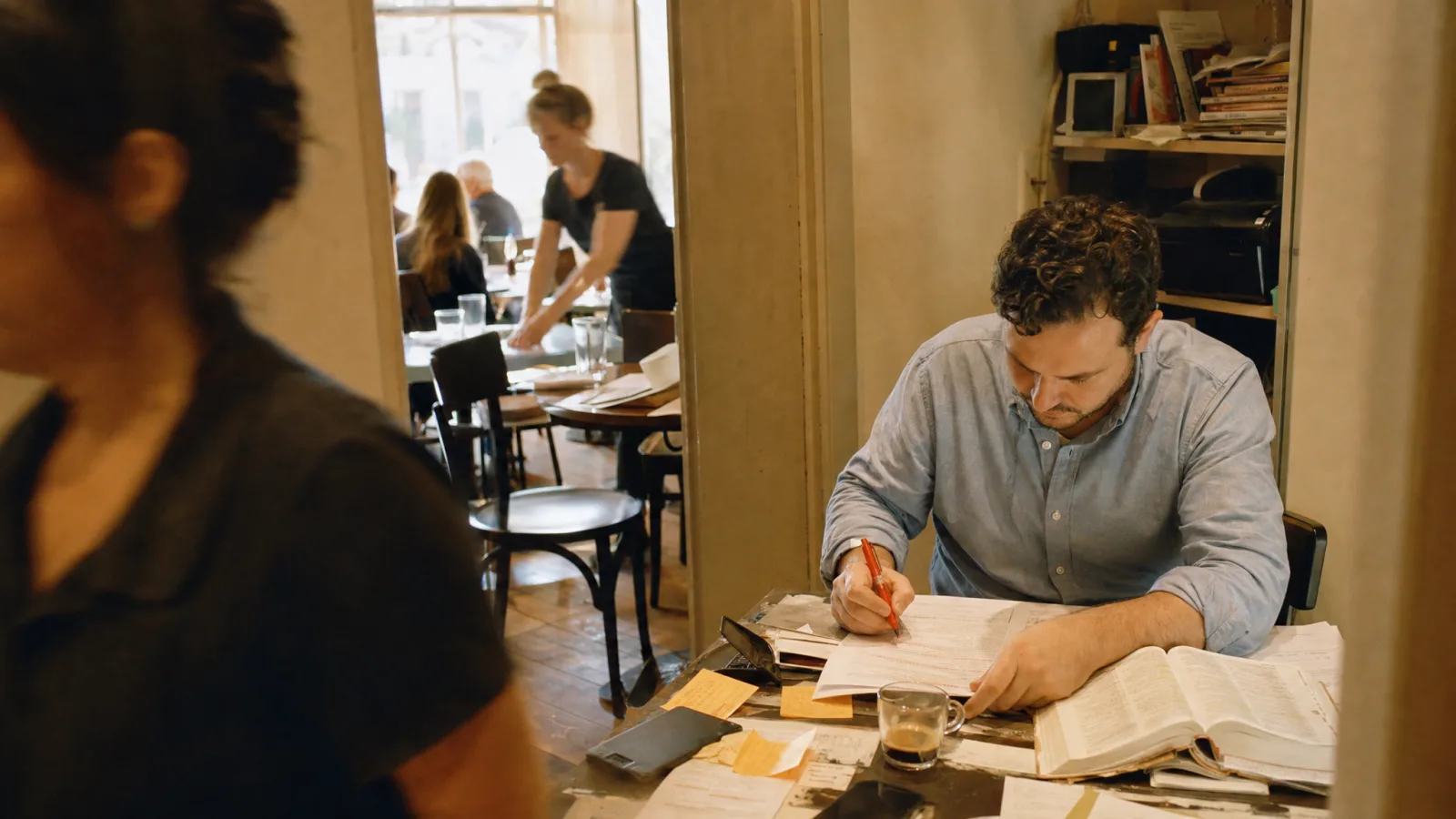 Titolare corregge in penna rossa le bozze del menu accanto a un dizionario inglese