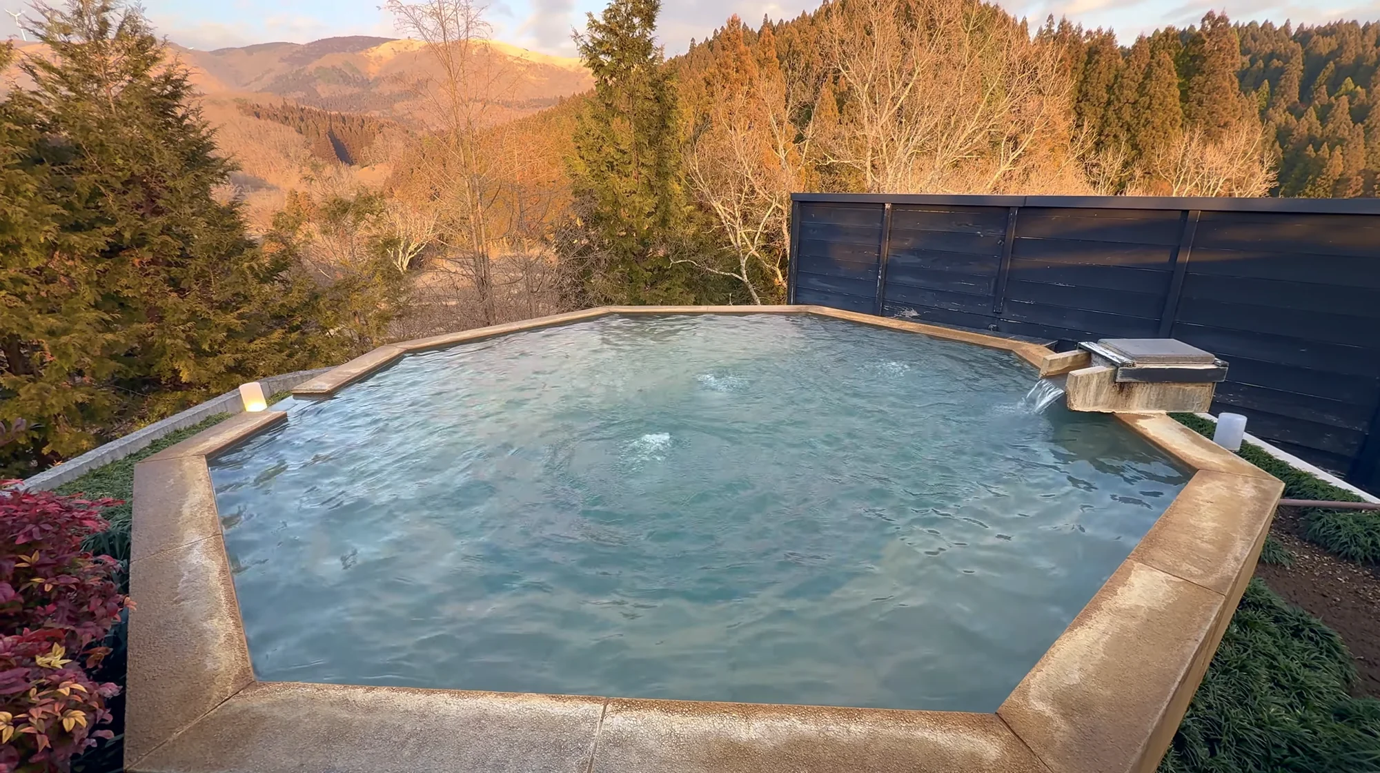A large open-air hot spring bath looking out over an autumn hillside