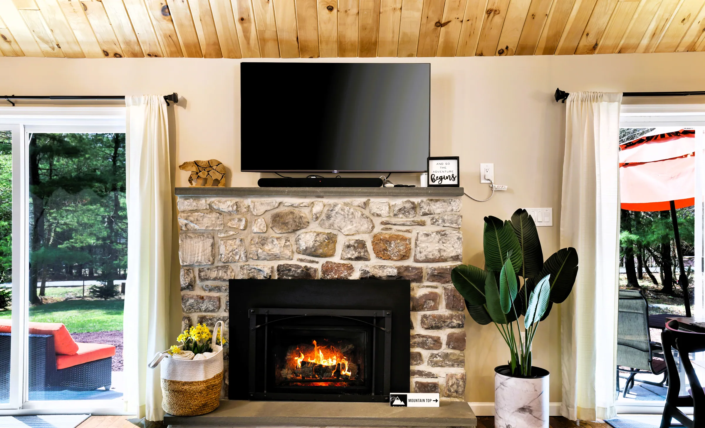 Stone gas fireplace with TV above between two sliding doors at Divine on Lupine