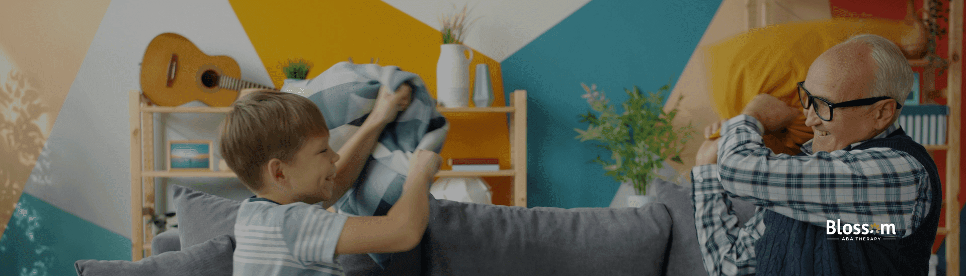 Old ABA therapist and autistic young boy playfully having a pillow fight on a couch after ABA therapy.