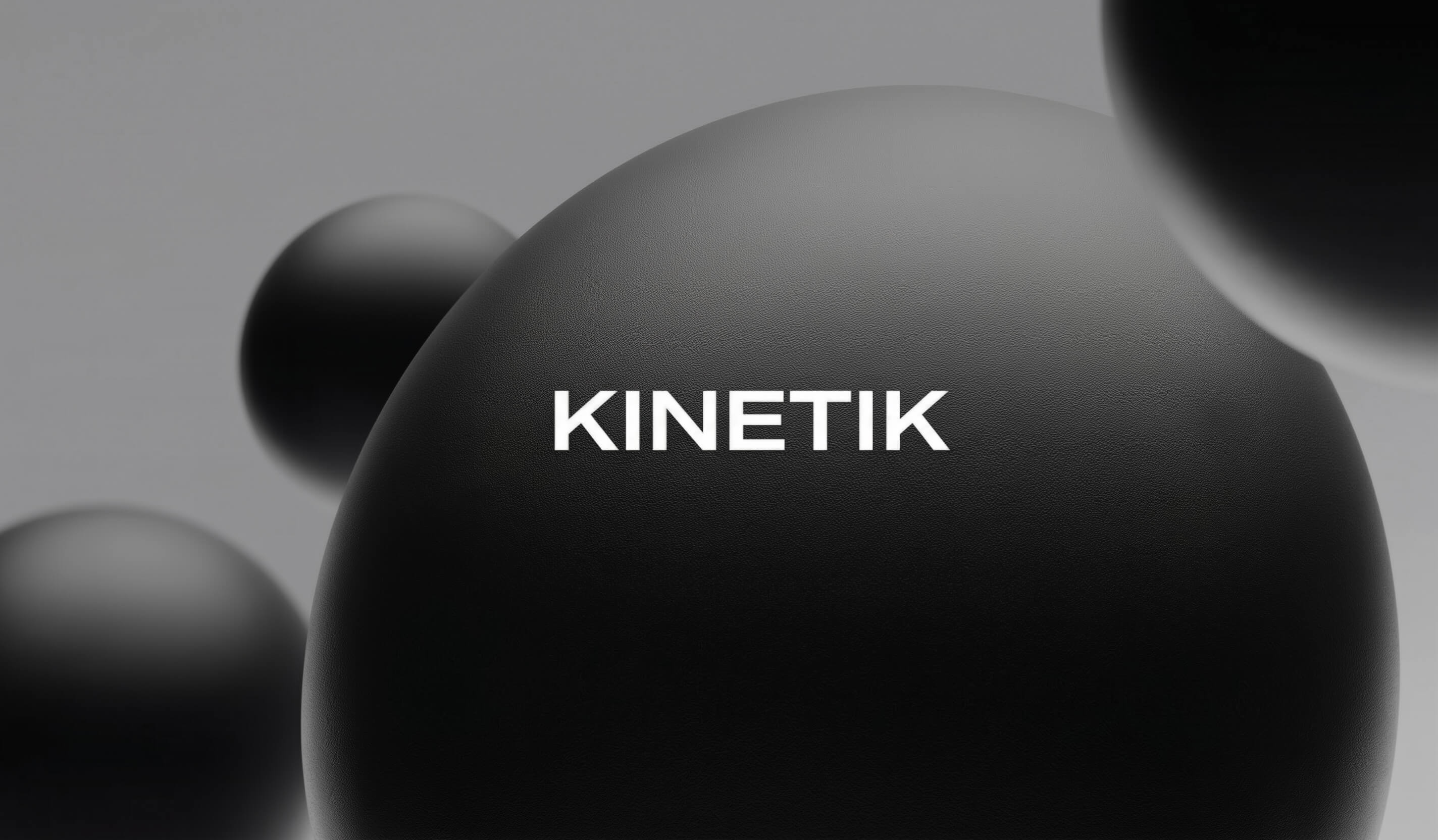 Minimalist 3D composition featuring matte black spheres with "KINETIK" typography in a clean, grey environment.