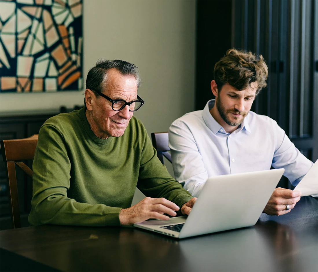 Vater und Sohn besprechen gemeinsam rechtliche Vorsorge am Laptop