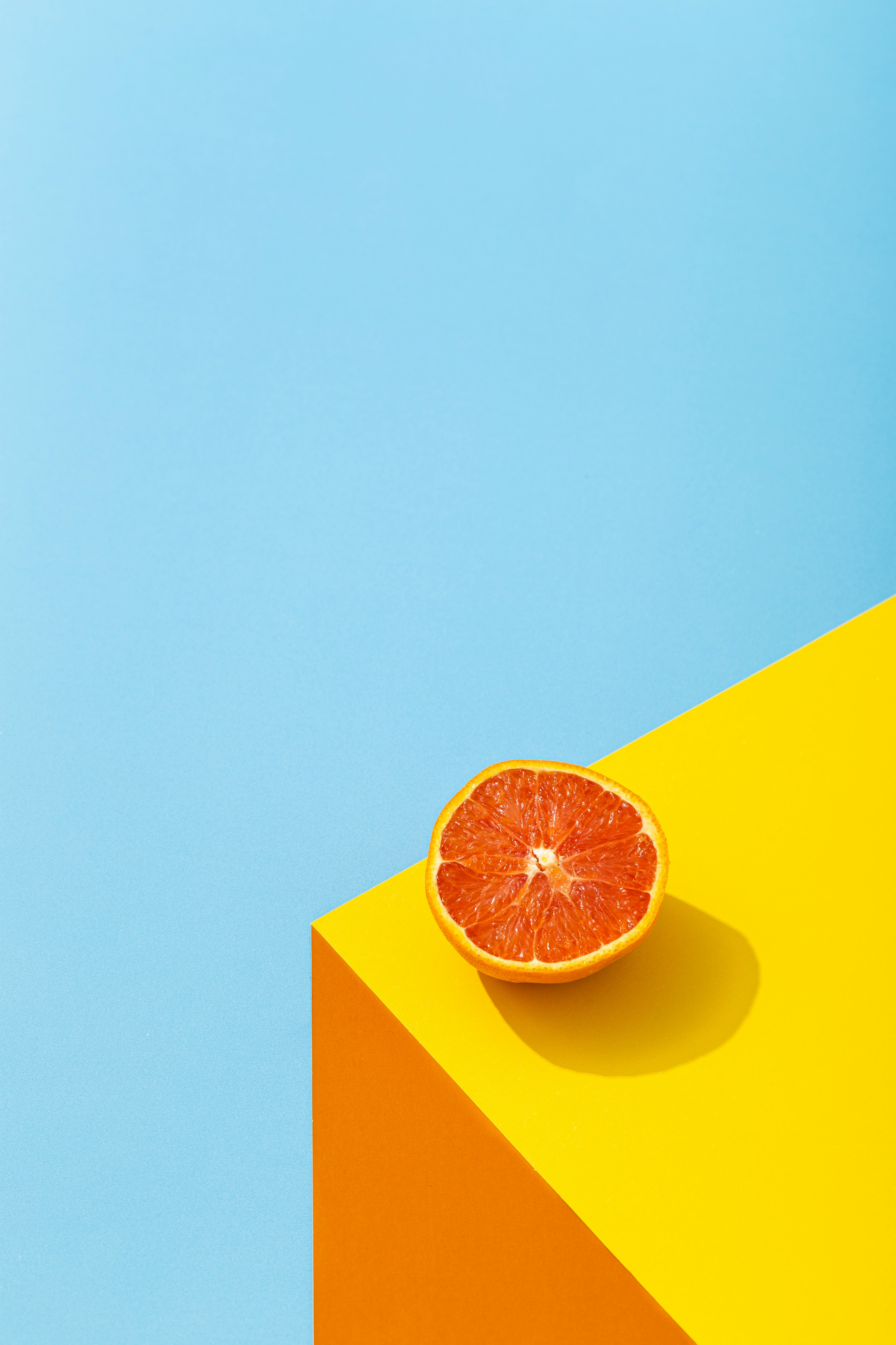 a half cut orange lying on a yellow table