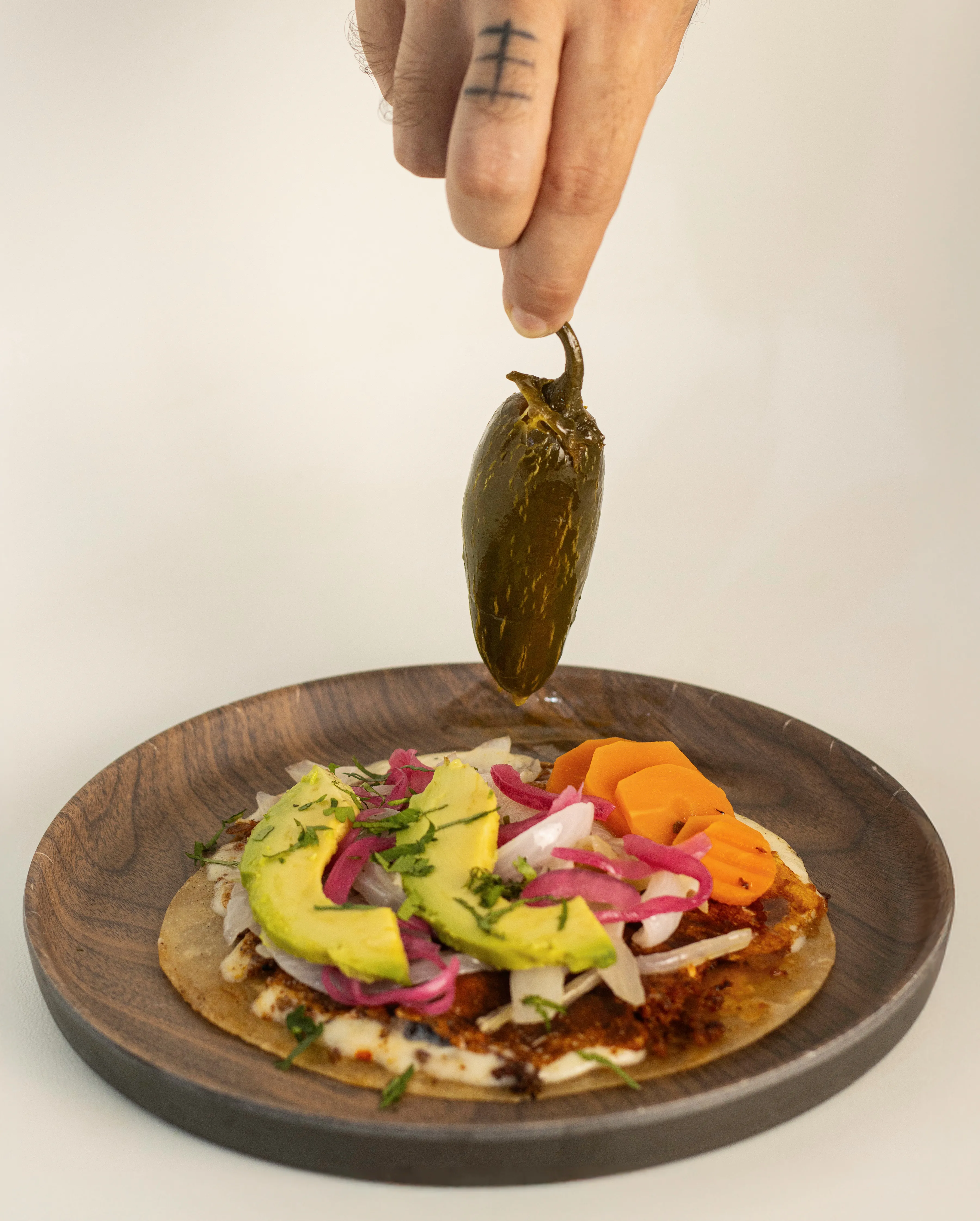 Preparación de taco con jalapeño en mano.