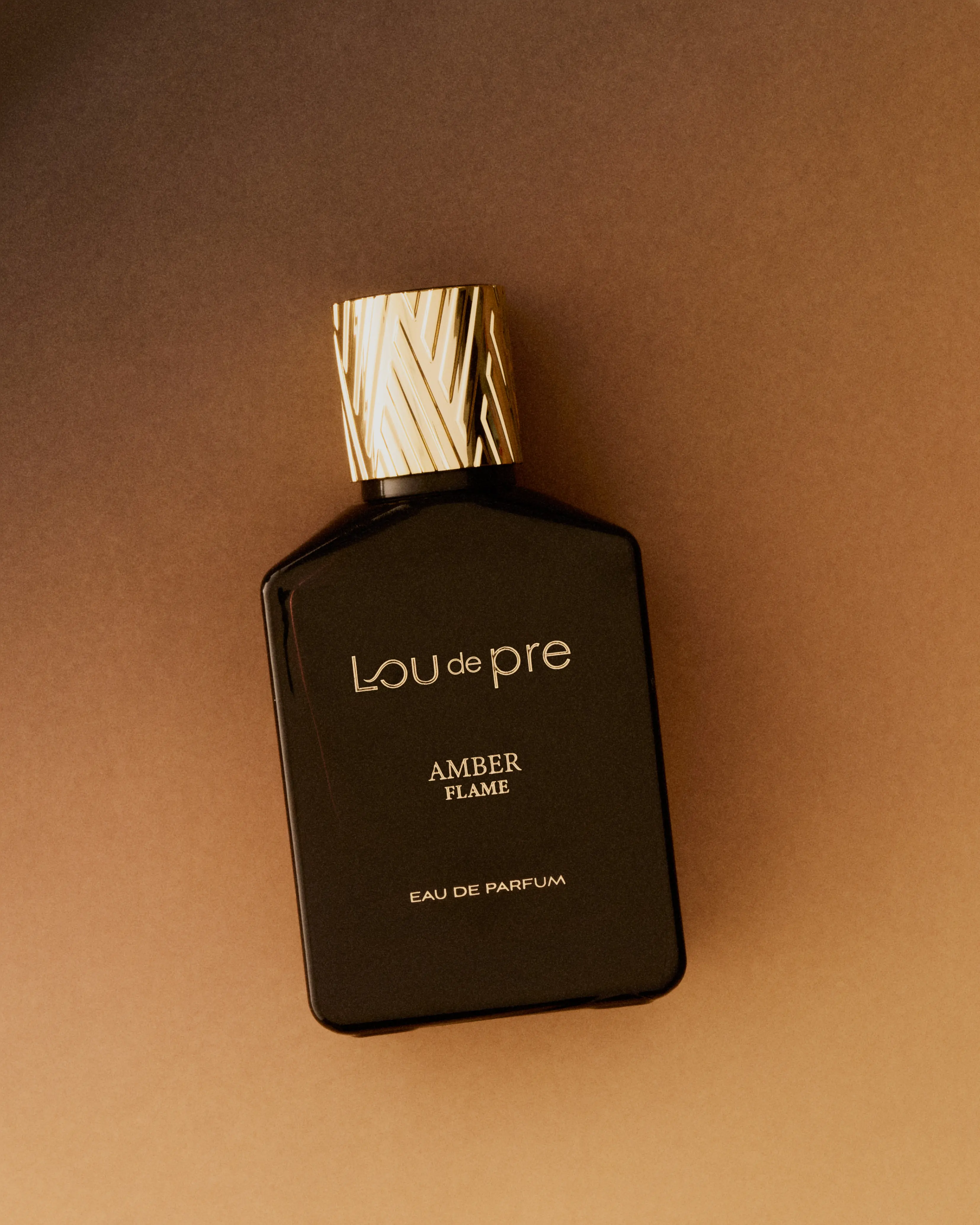 flakon perfum Lou de Pre leżących na brązowym tle