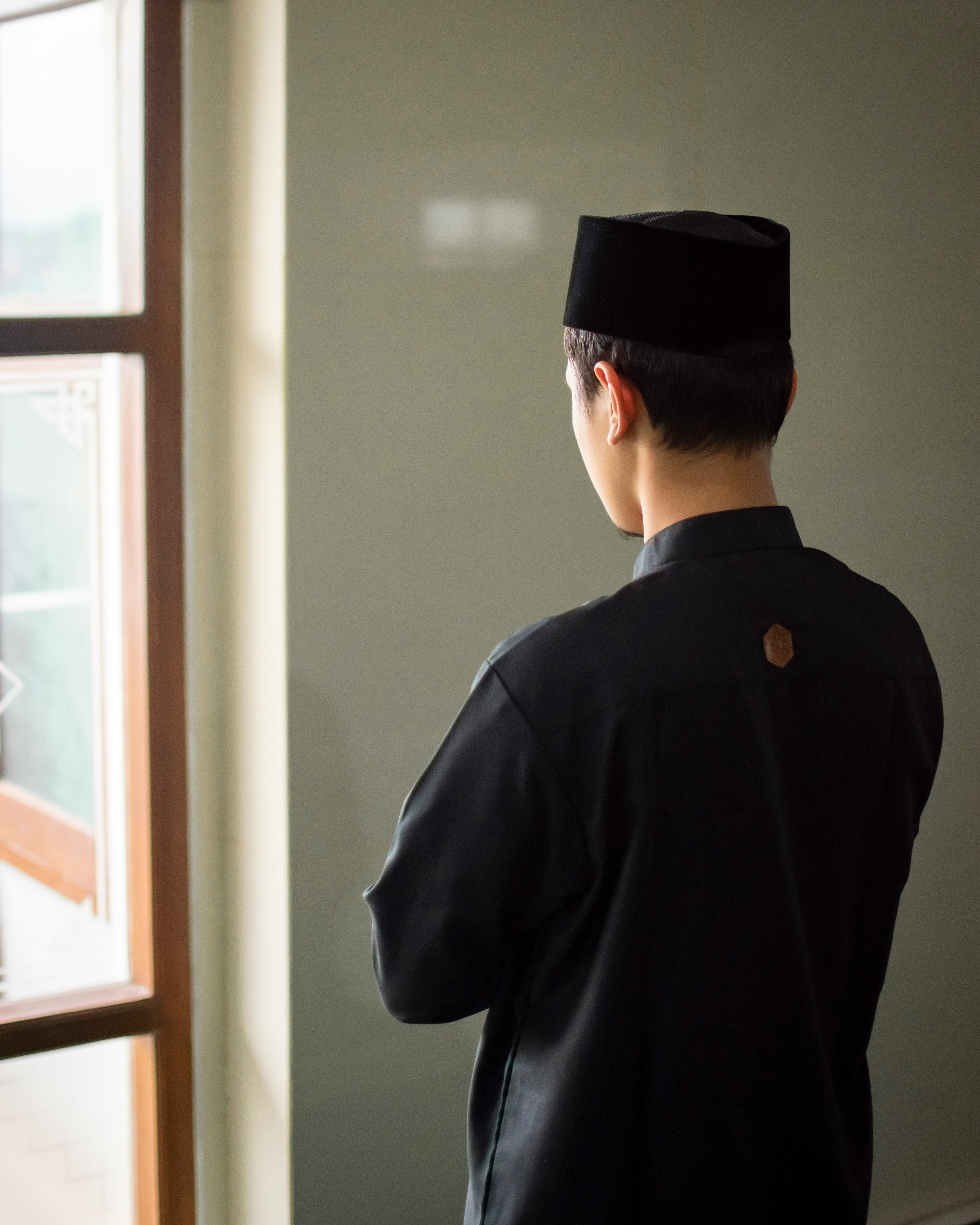 a man in a black outfit looking out a window