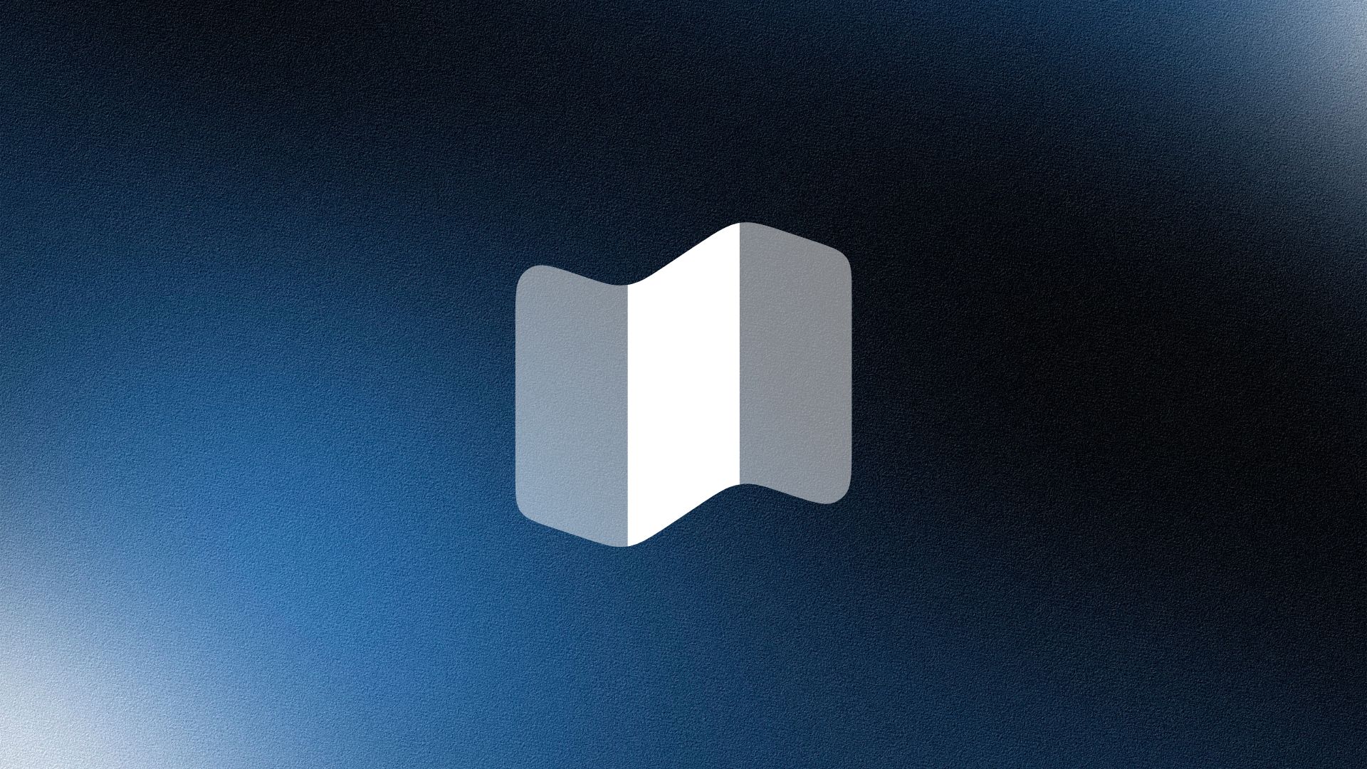 Smiling woman wearing a beige blazer and grey shirt, holding a folder while standing by a sunlit wall.