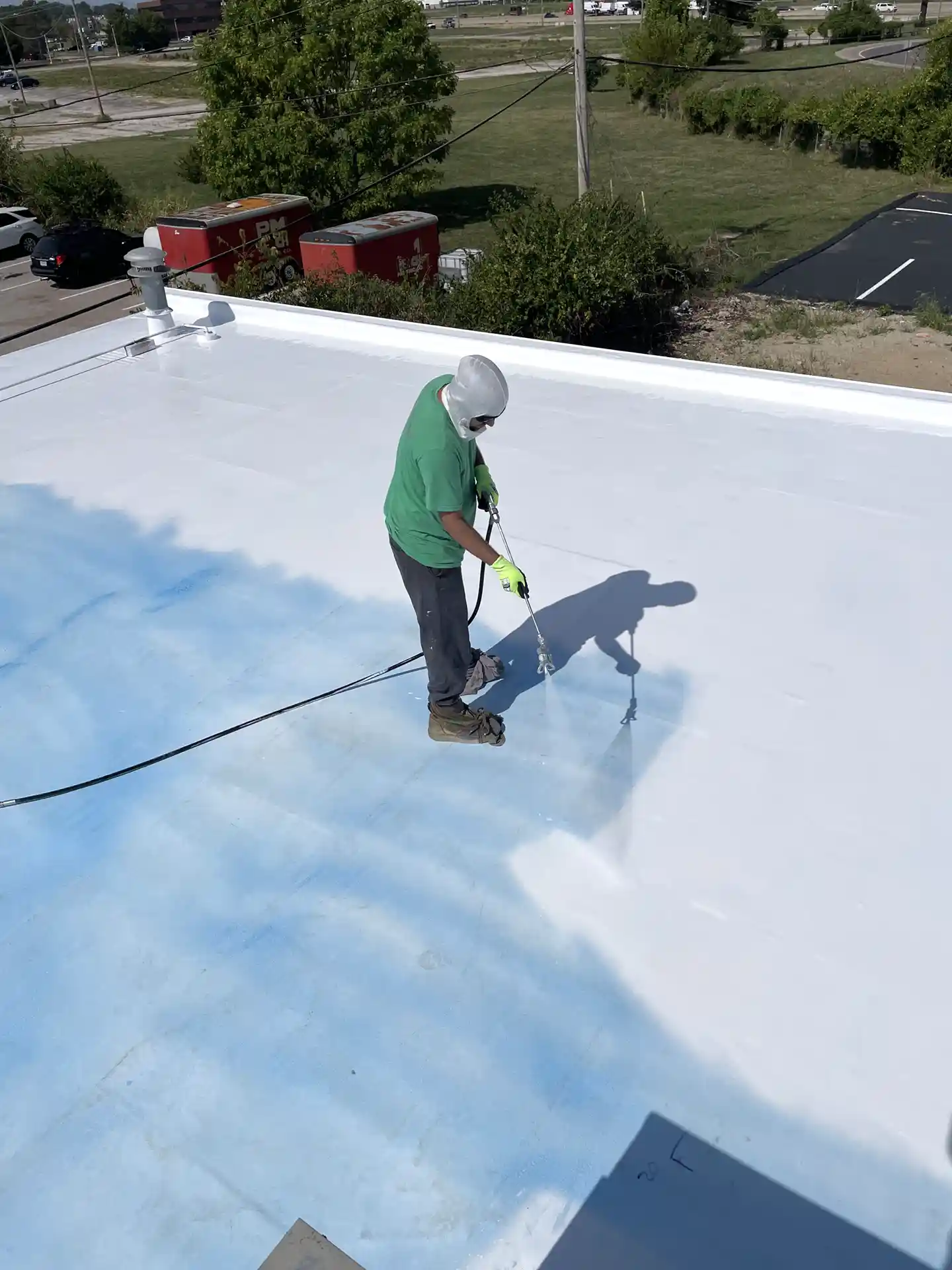Un homme applique un revêtement de silicone sur le toit d'un bâtiment de bureaux