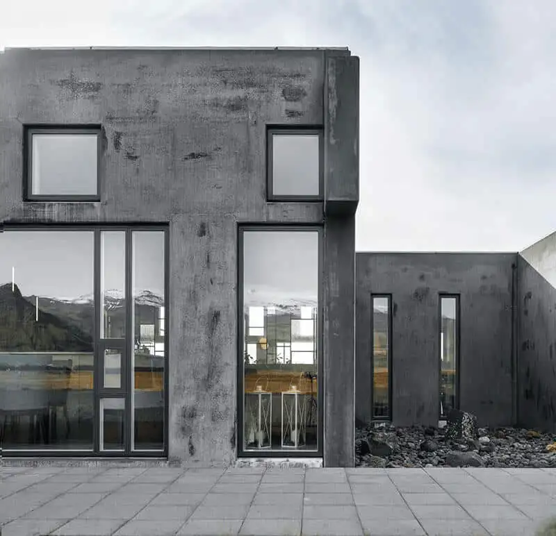 Close-up of the hotel's weathered concrete facade with tall windows reflecting the mountains