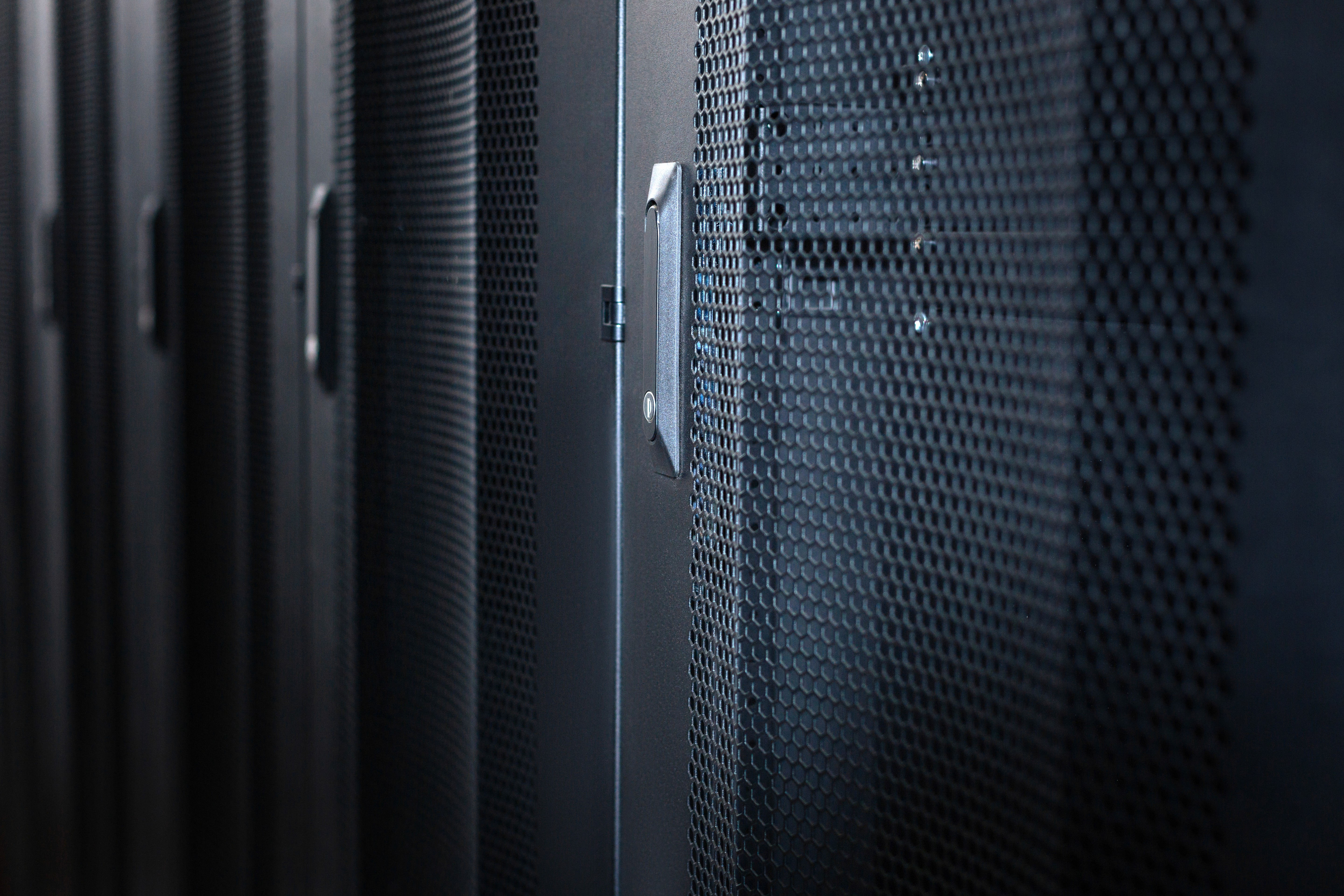 Close-up of perforated black server cabinet doors in a data hall
