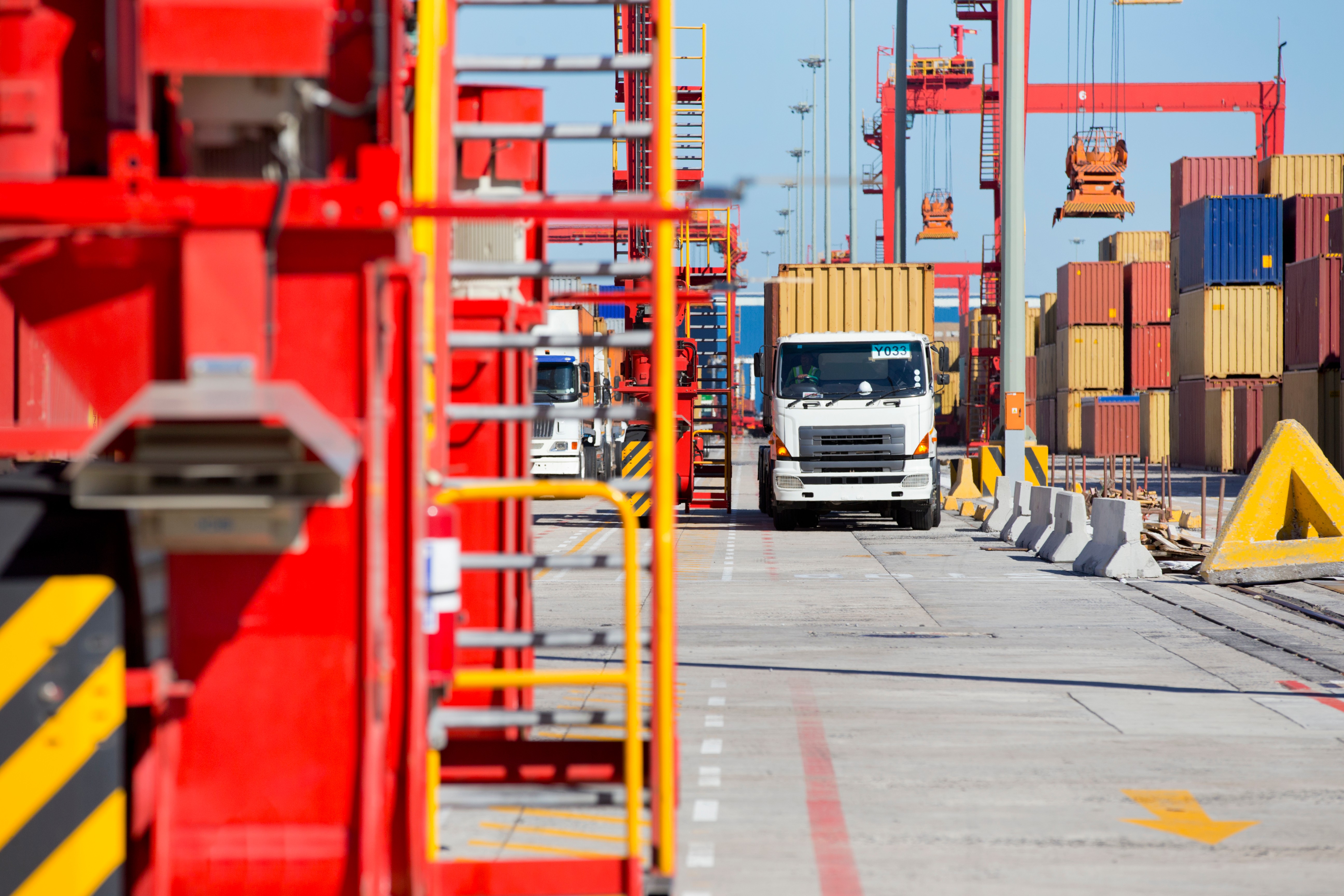 Young woman smiling brightly near a frosted glass whiteboard, bathed in warm, natural light in a modern office setting.