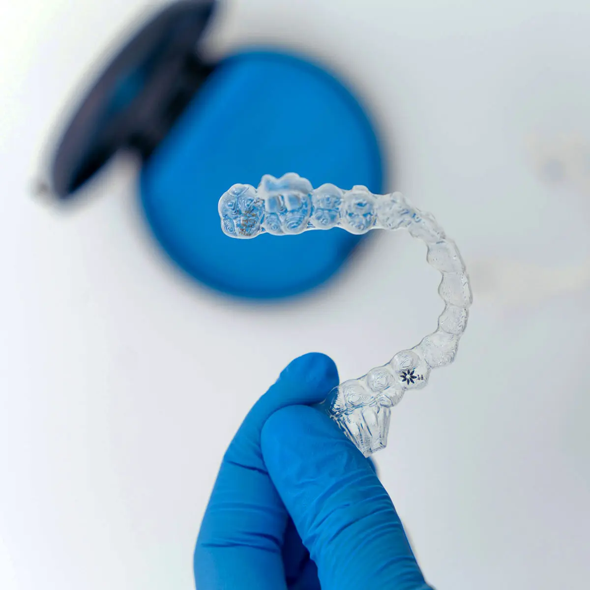 Hands with gloves holding invisalign.