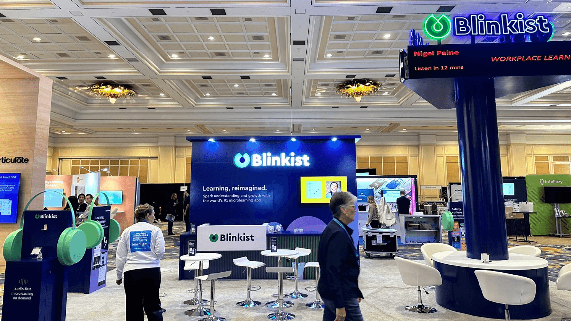 Blinkist DevLearn Conference & Expo 2025 20x40 technology product demo booth with front presentation wall, reception desk, demo screen, meeting tables, and lounge seating