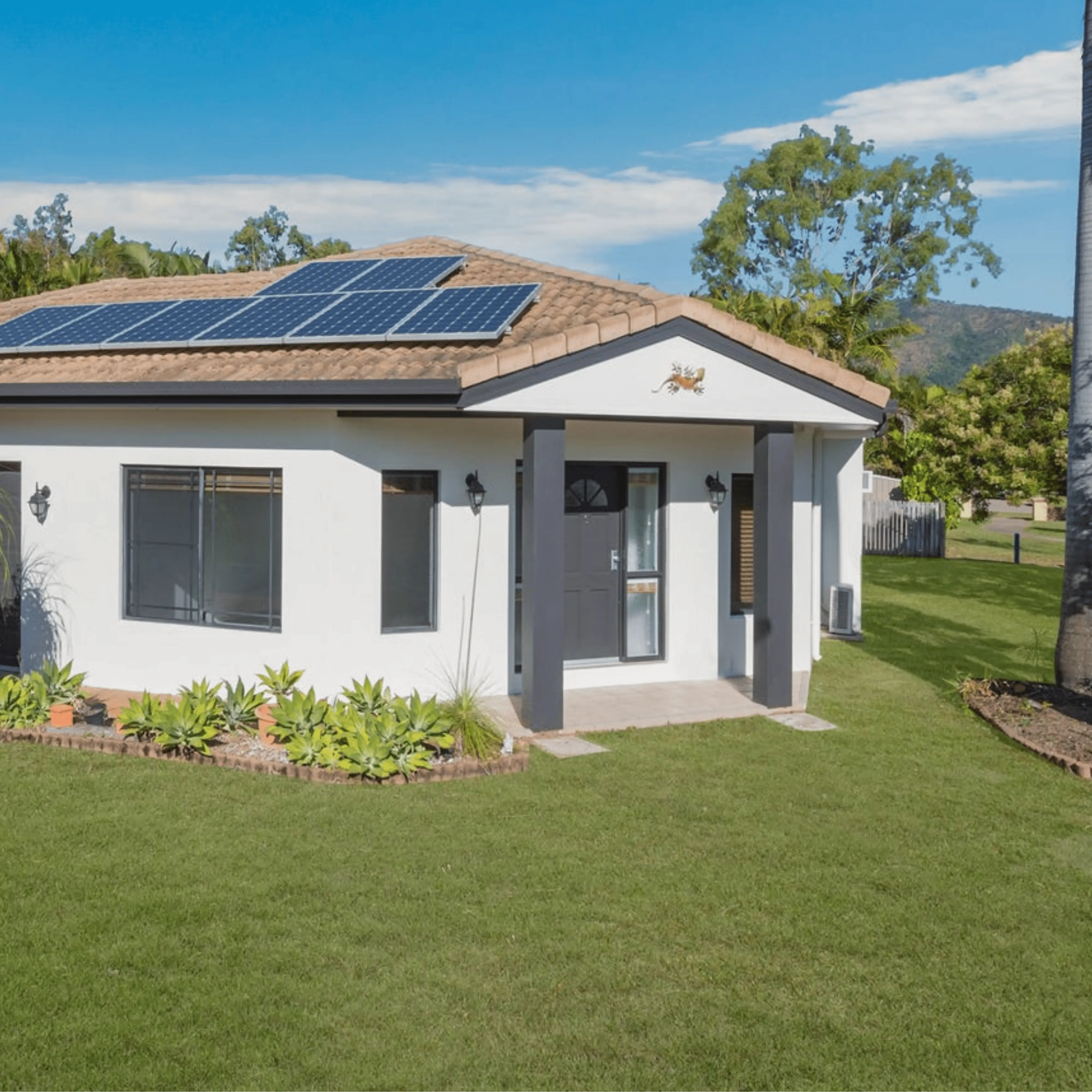 White house with solar panels and green lawn.