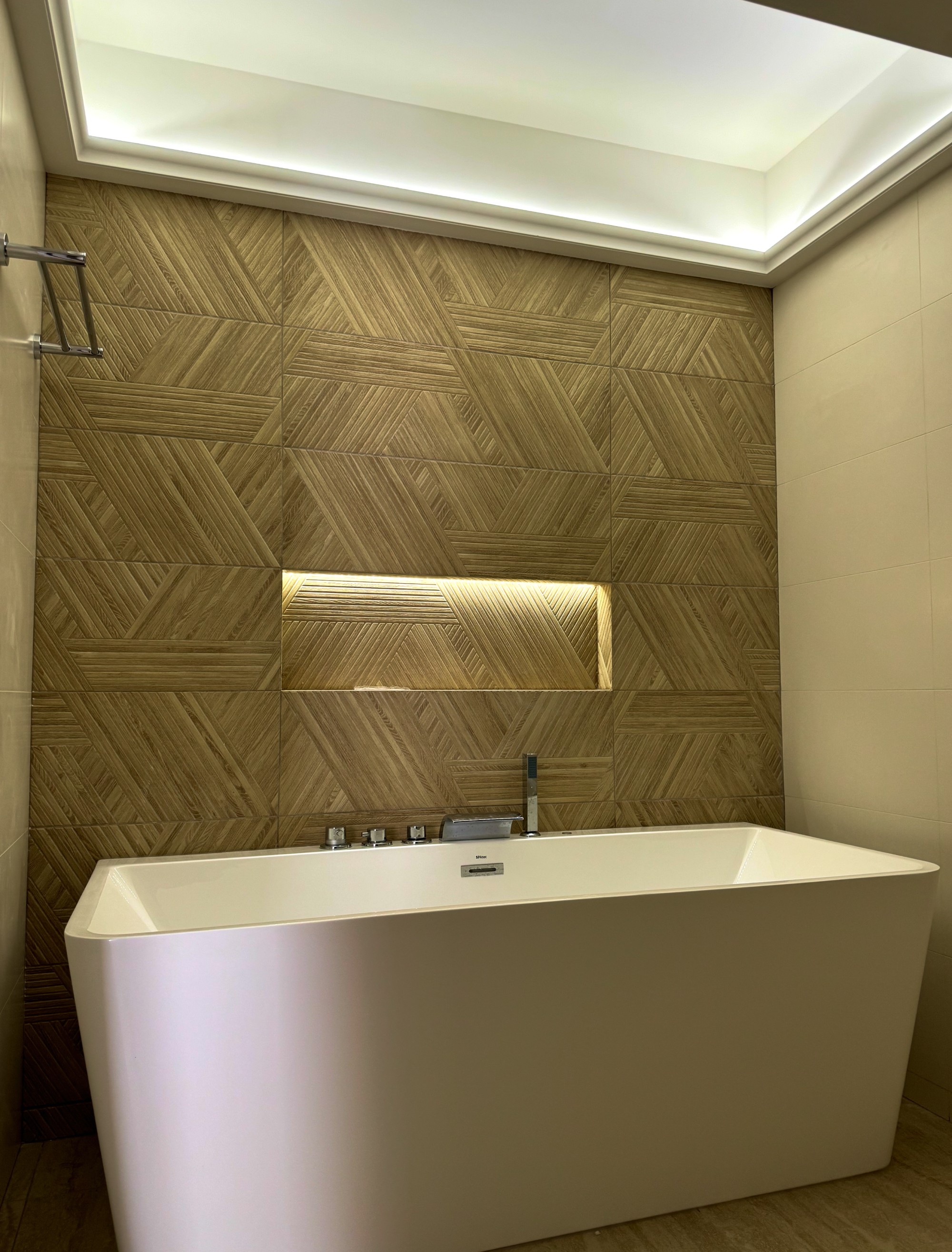 Design de salle de bain avec mur en pierre texturée et niche lumineuse au-dessus de la baignoire.