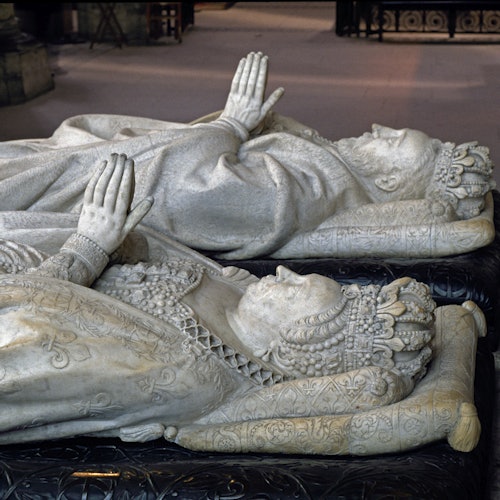 装饰华丽的大理石雕像，描绘了一对身着皇冠的男女并排躺着，双手合十祈祷。