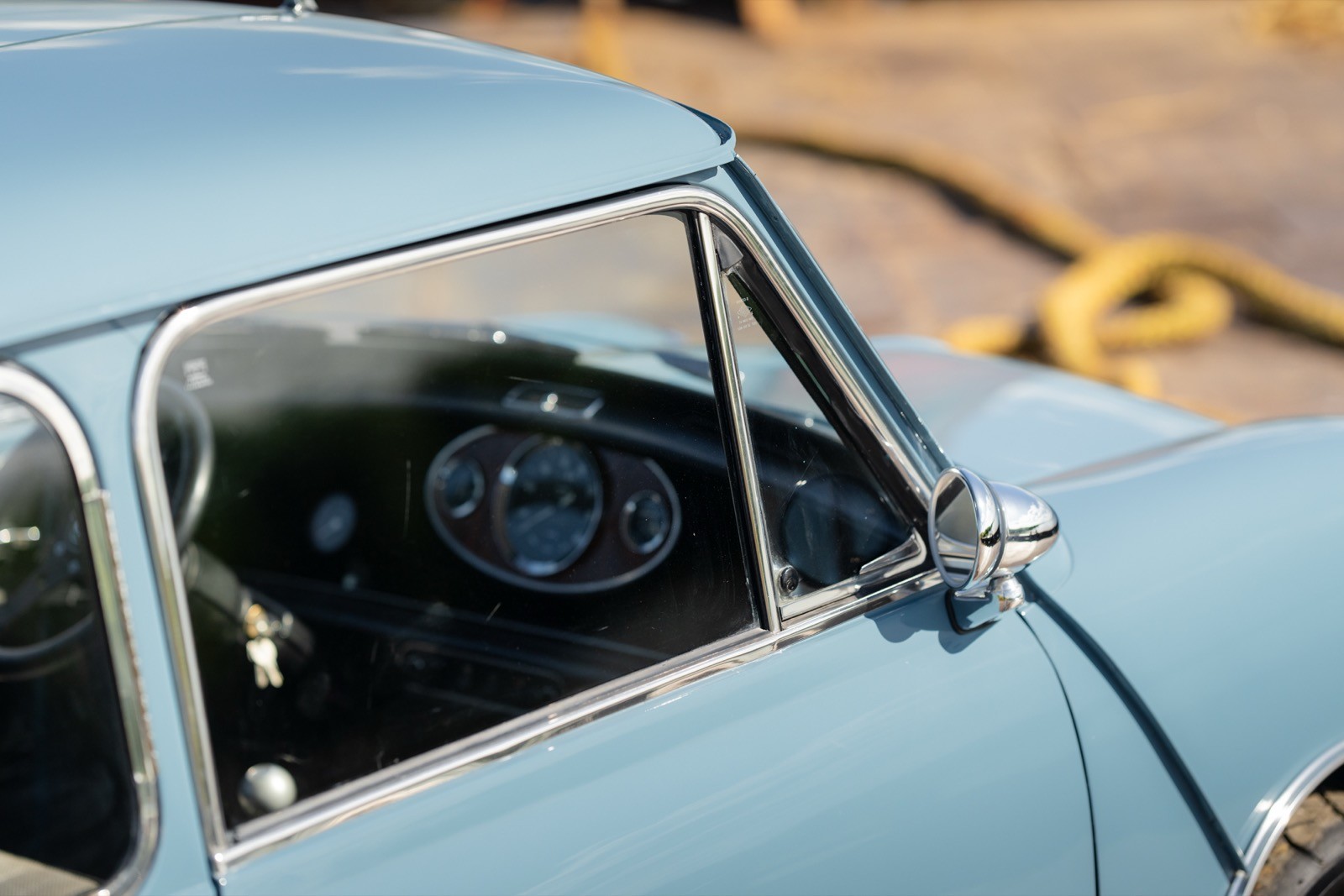Close-up of a vintage car interior showing the steering wheel and dashboard through the driver's side window.